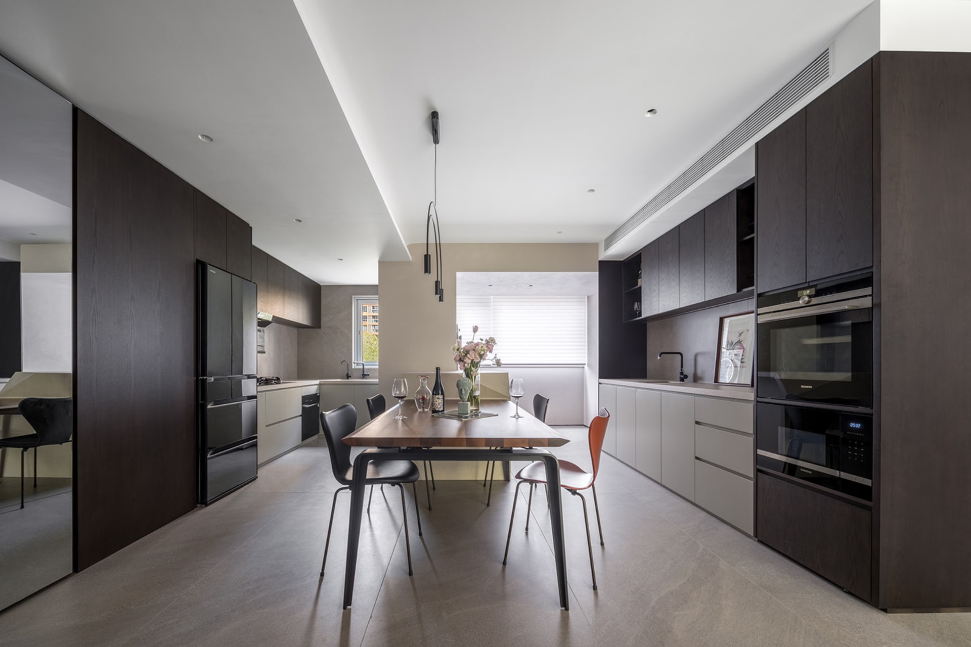 Modern kitchen with wooden countertops and table, featuring stainless steel appliances and a large window.