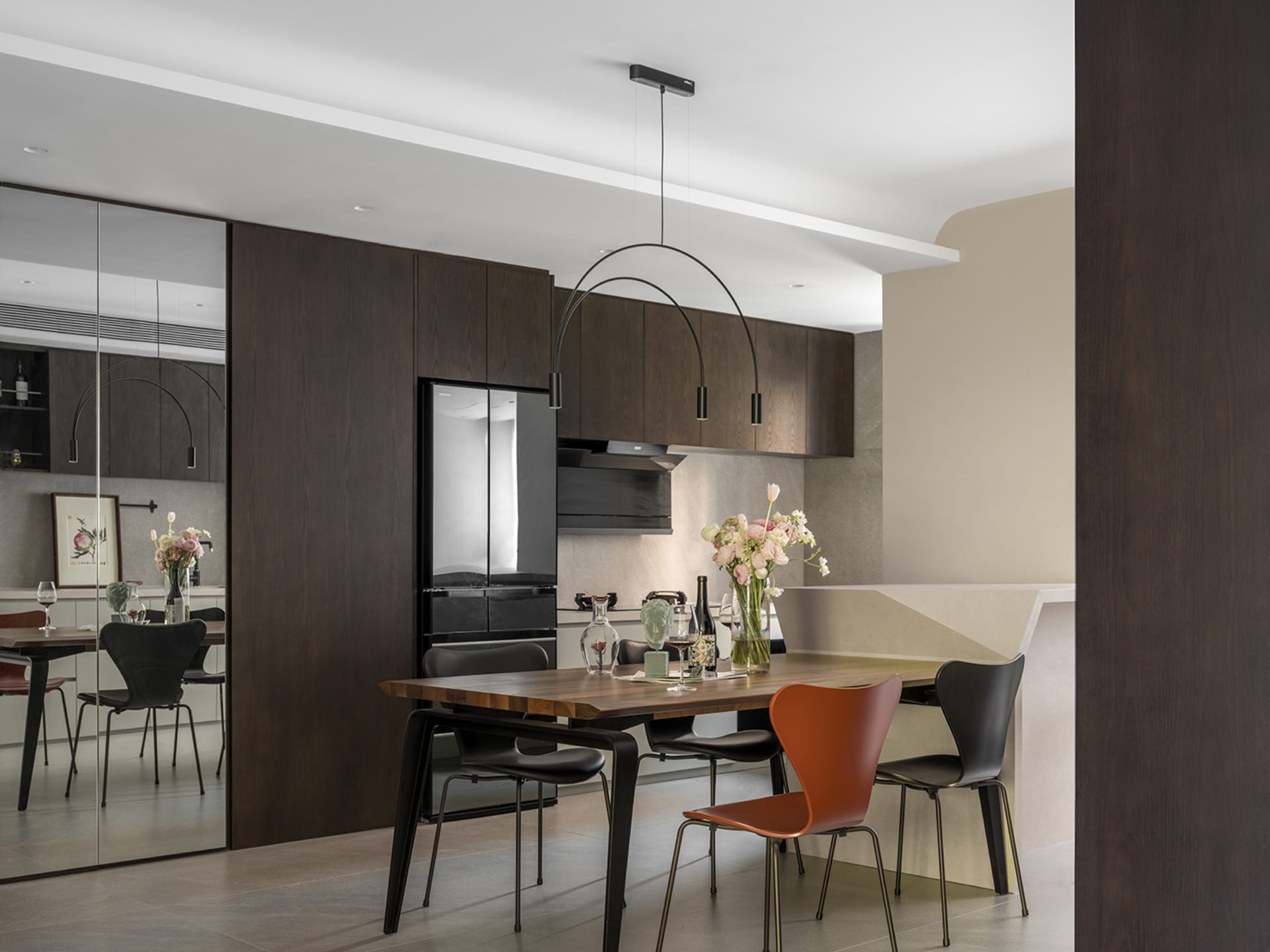 A modern kitchen with wooden furniture mix, featuring a dining table, chairs, and a refrigerator.