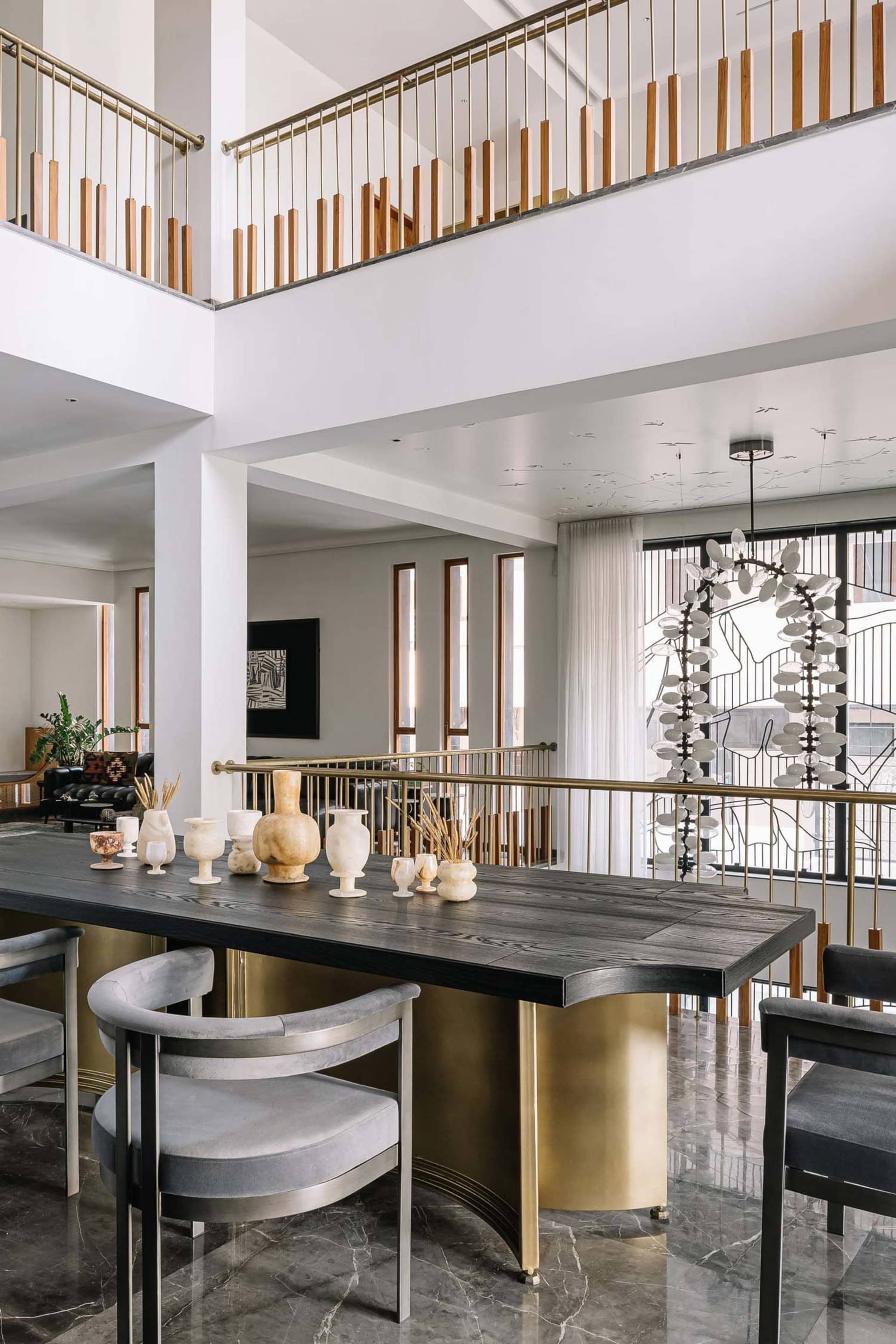Modern dining room featuring a sleek black marble table with contemporary chairs, positioned against a modern staircase with