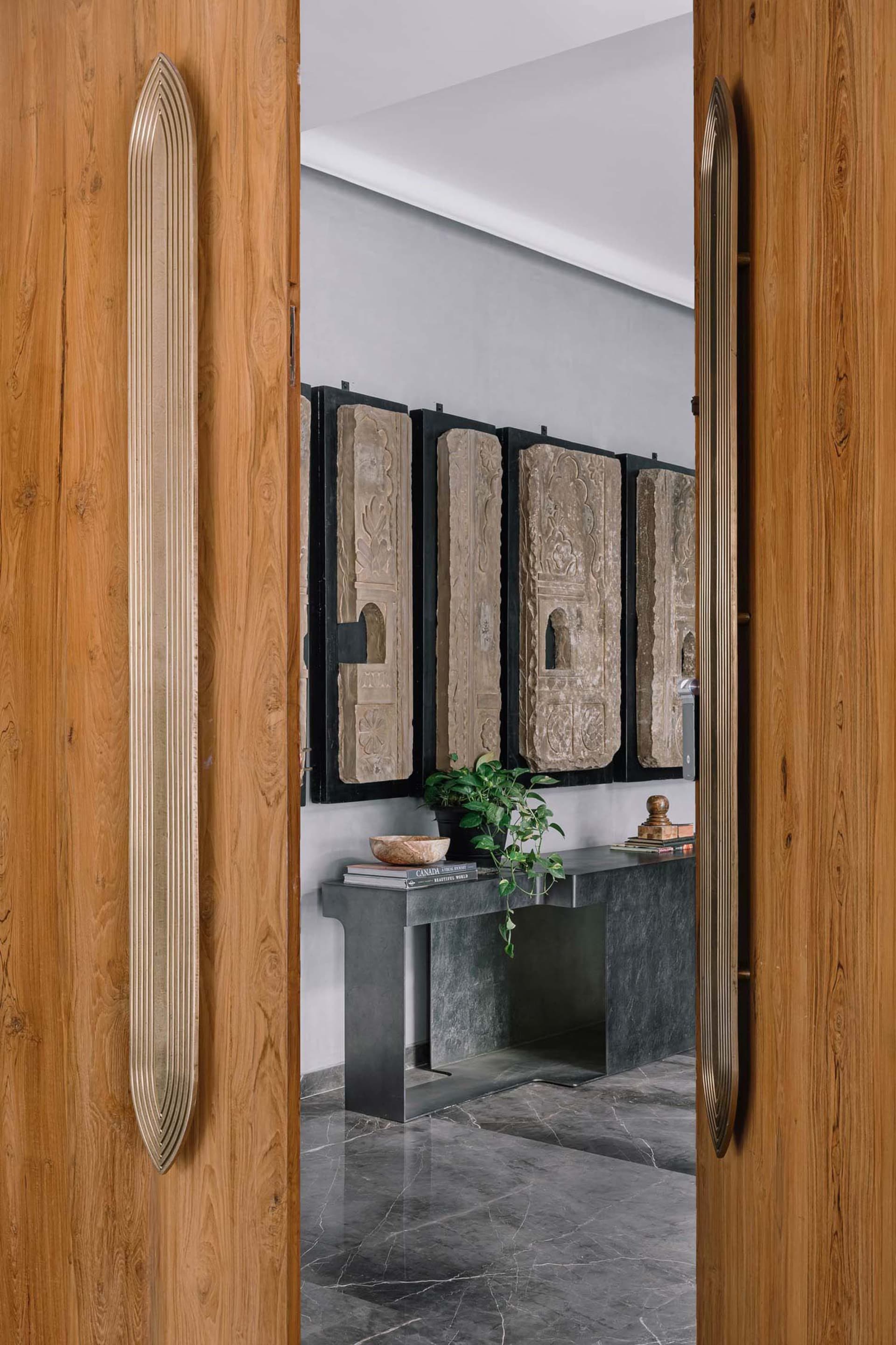 Entrance hall featuring modern design with wooden doors, concrete flooring, and carved stone panels.