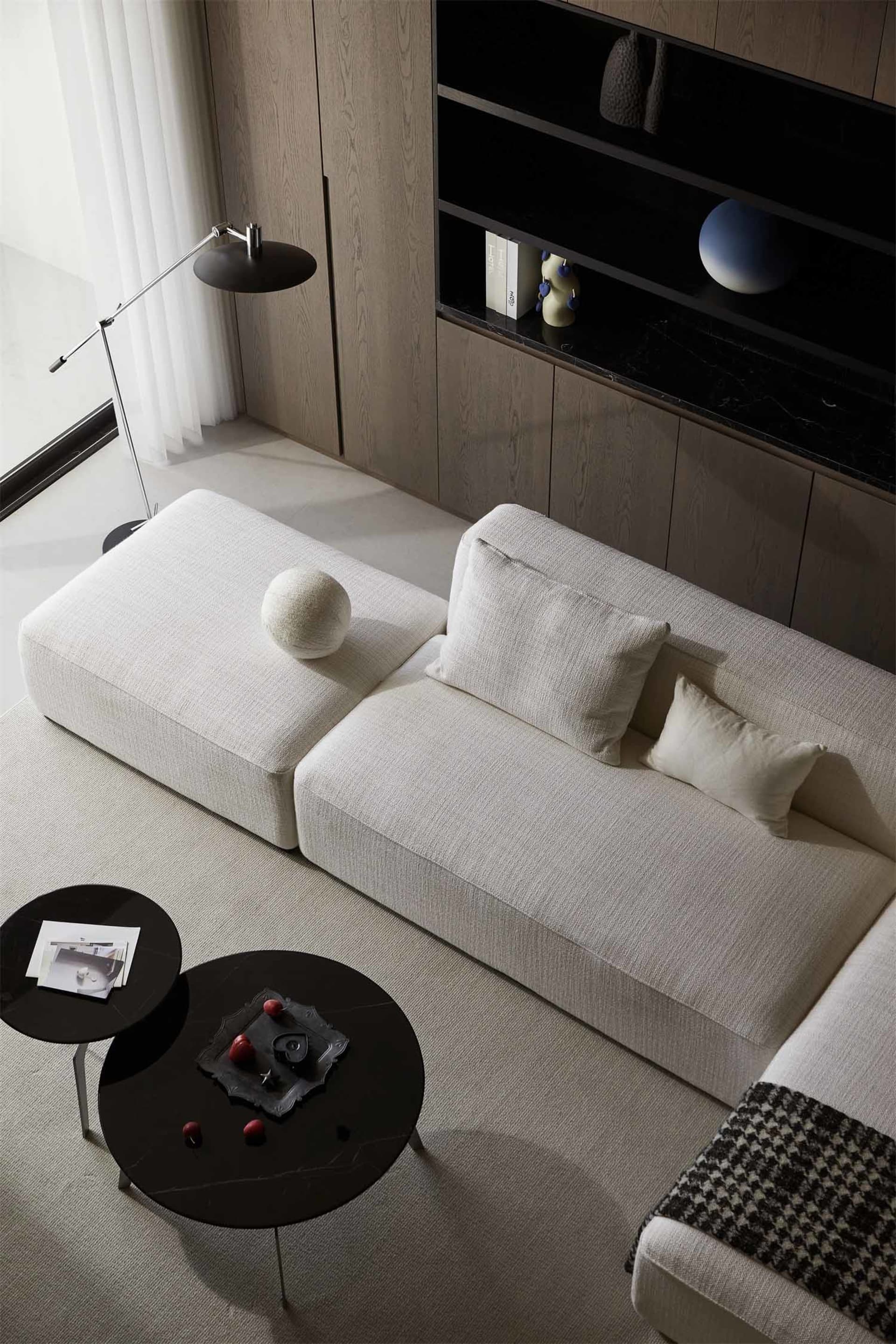 Modern living room featuring fabric couches and marble side tables.
