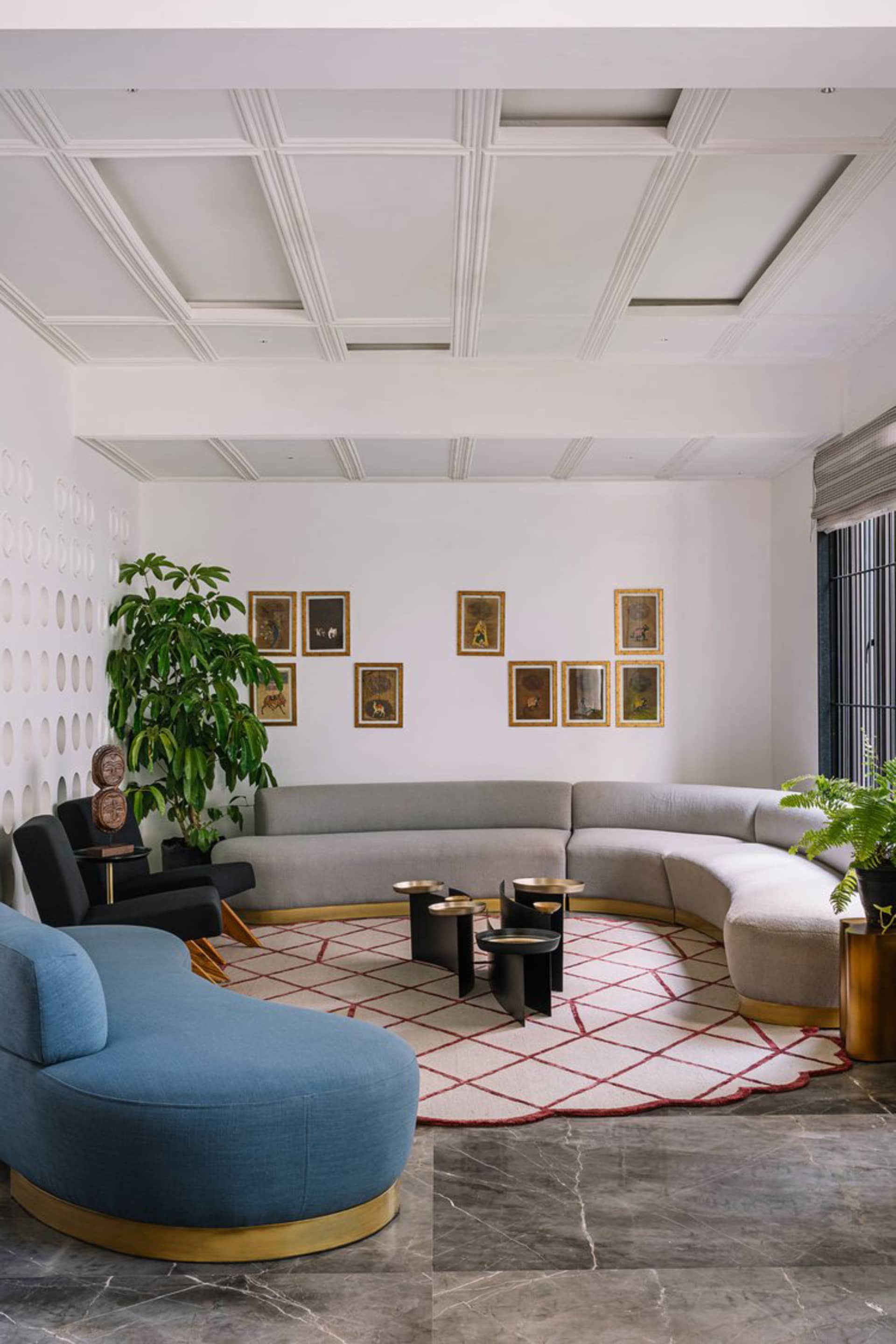 A modern living room featuring gray couches on a marble floor with framed artwork on the wall.