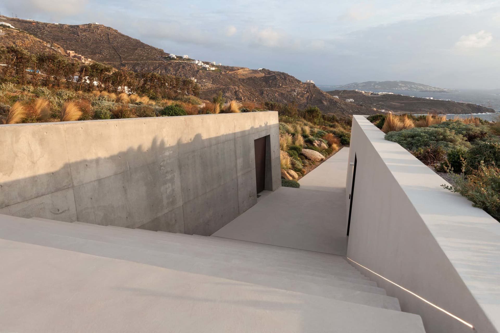 A modern residential building with a concrete staircase leading to the entrance.