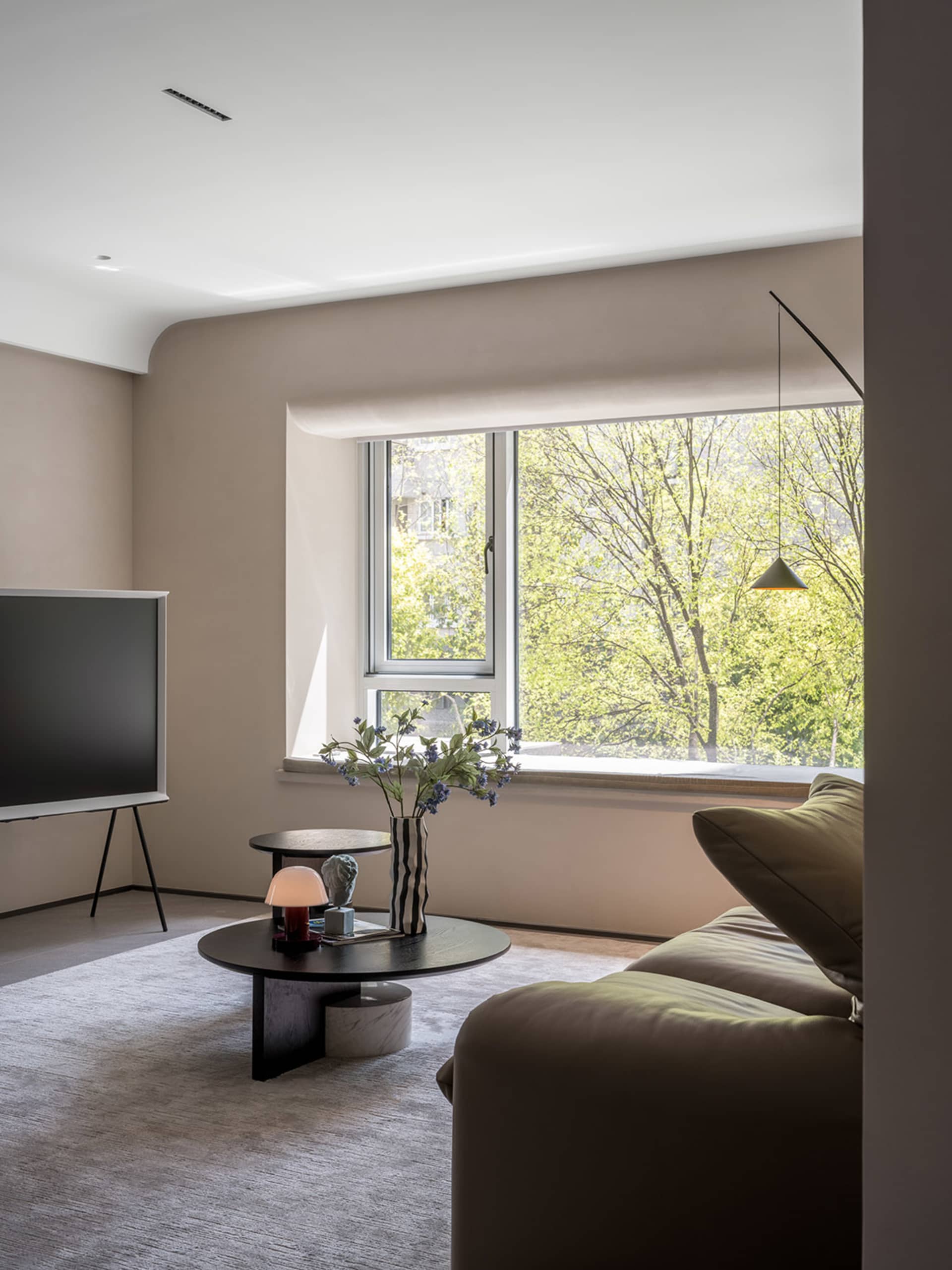 Modern living room featuring a minimalist couch and contemporary coffee table with a vase of flowers, in a contemporary desig