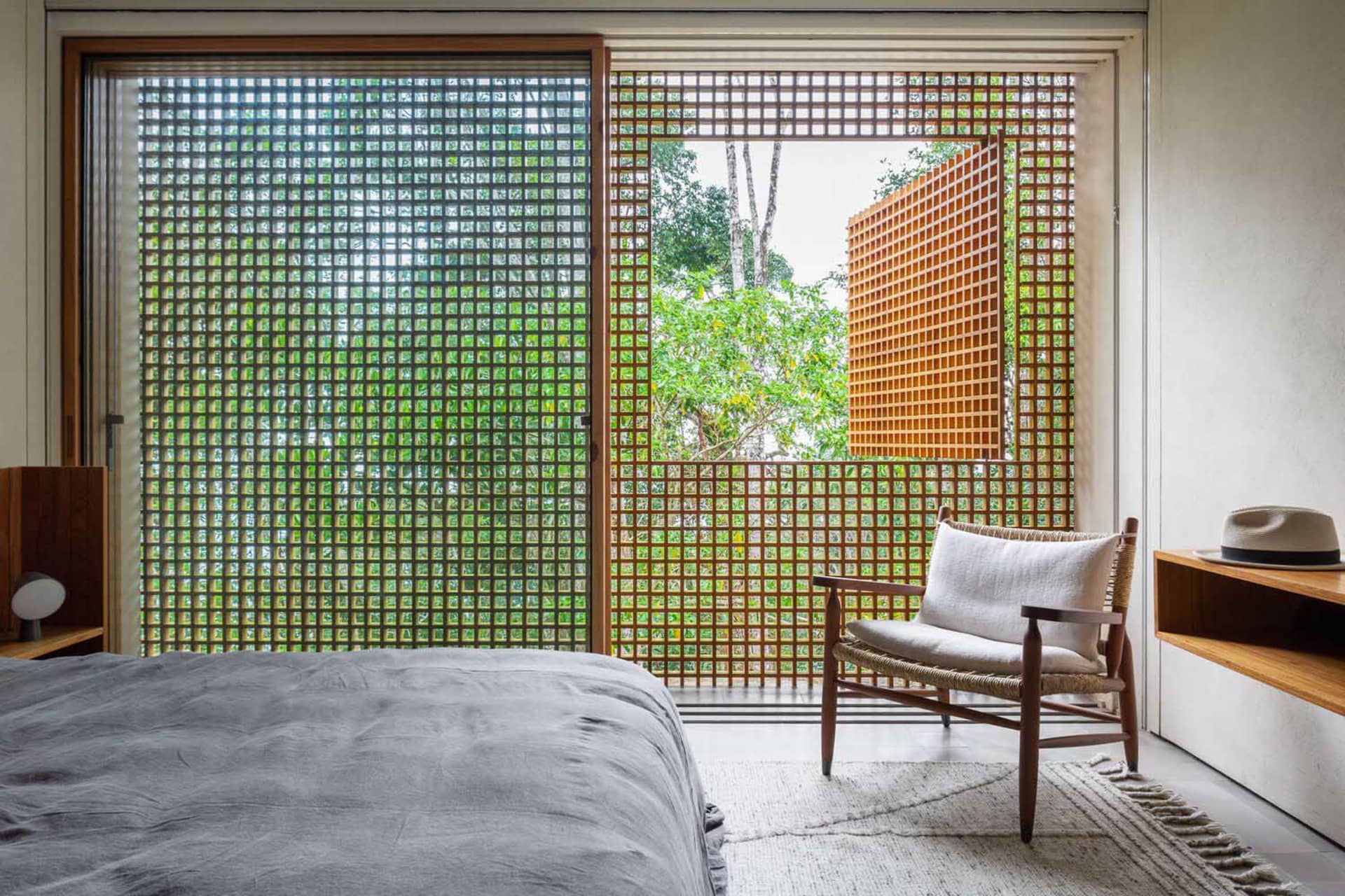 A modern bedroom with glass walls and a single white armchair.