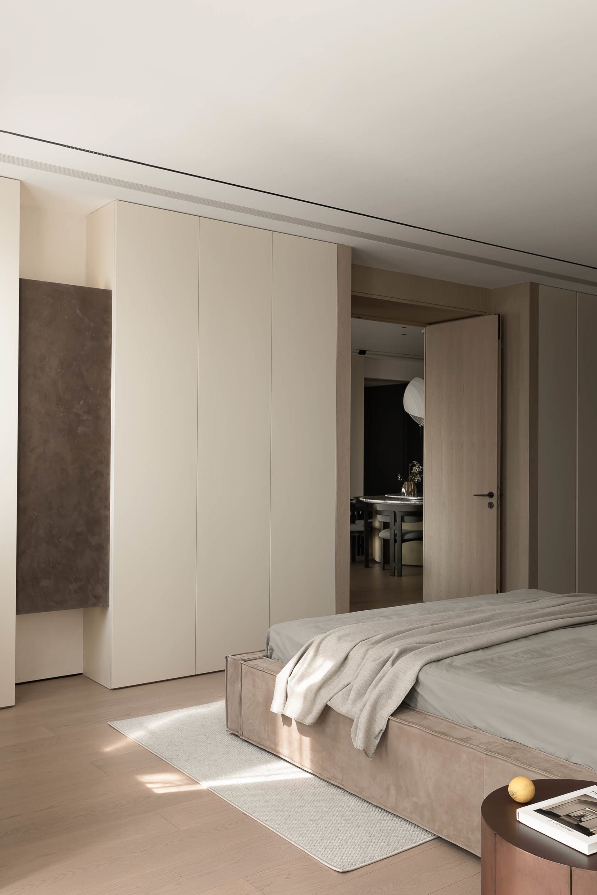 A modern bedroom featuring a bed with a neutral-toned blanket and a large closet in the same color palette.