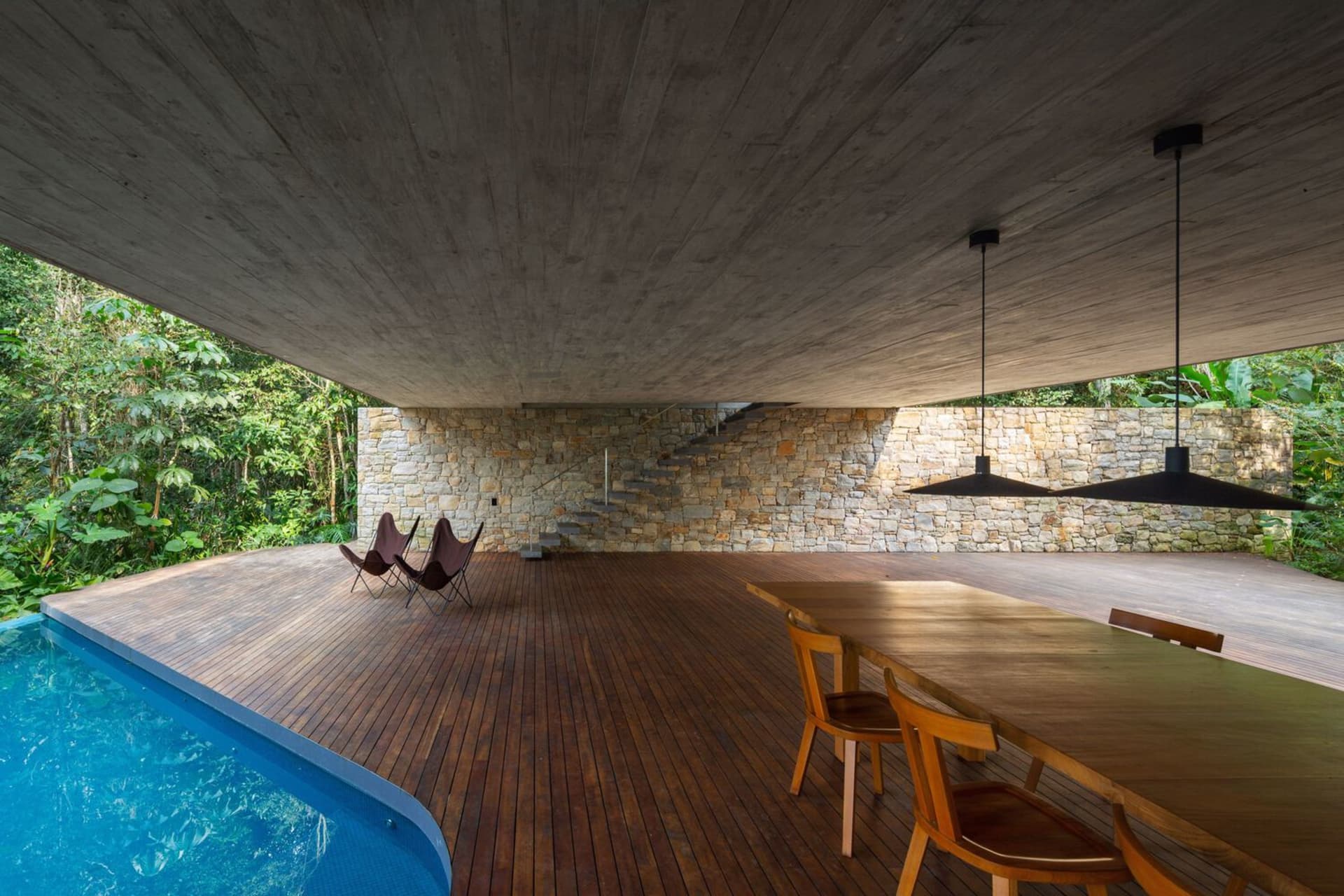 Modern living room with a large pool, concrete walls, and wooden floors.