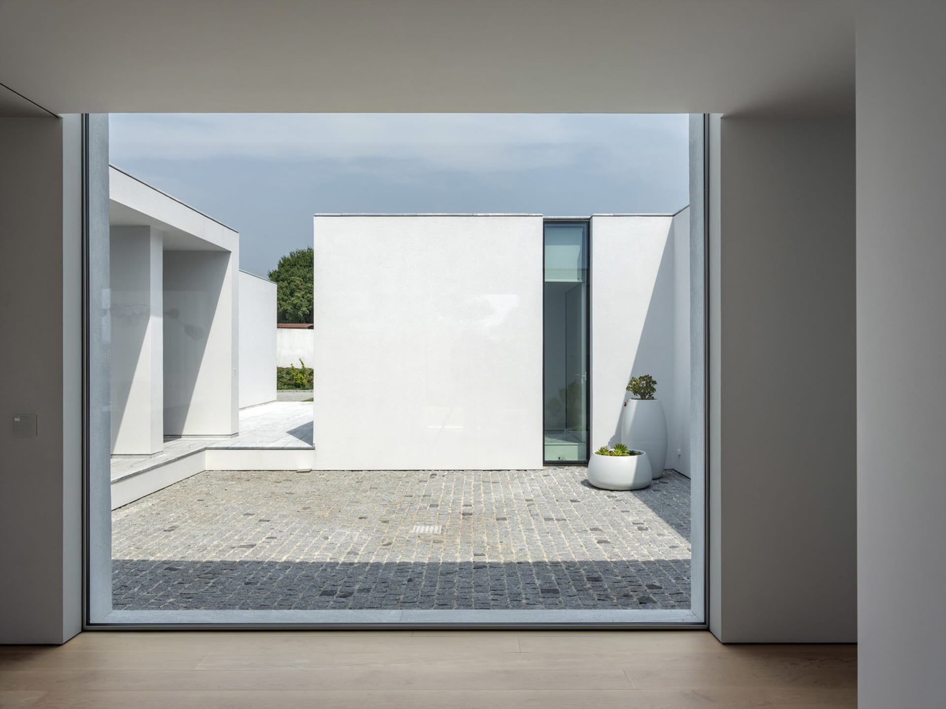 Modern interior space featuring white walls, concrete flooring, and glass elements.