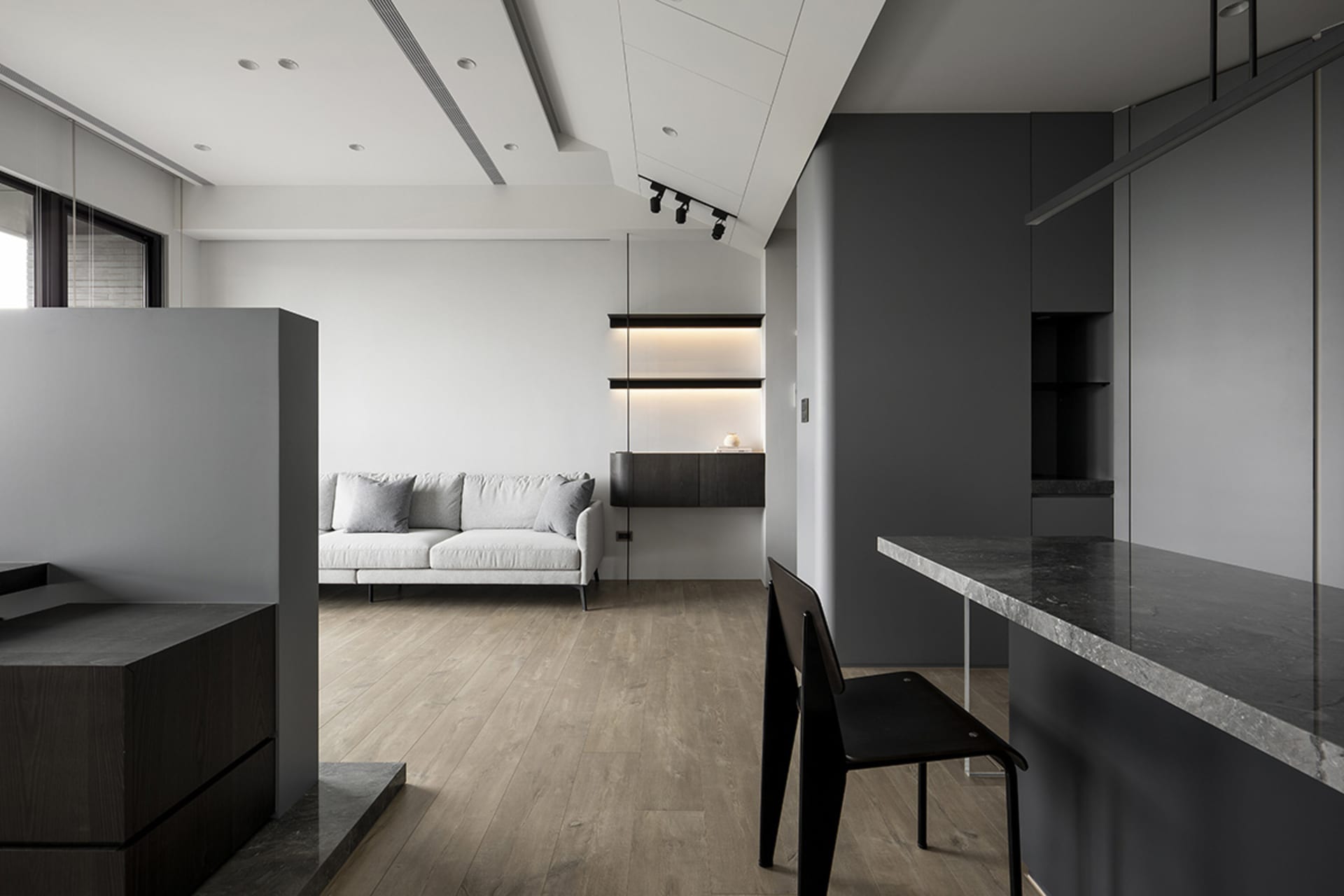 A minimalist living room featuring a concrete floor and wooden furniture.