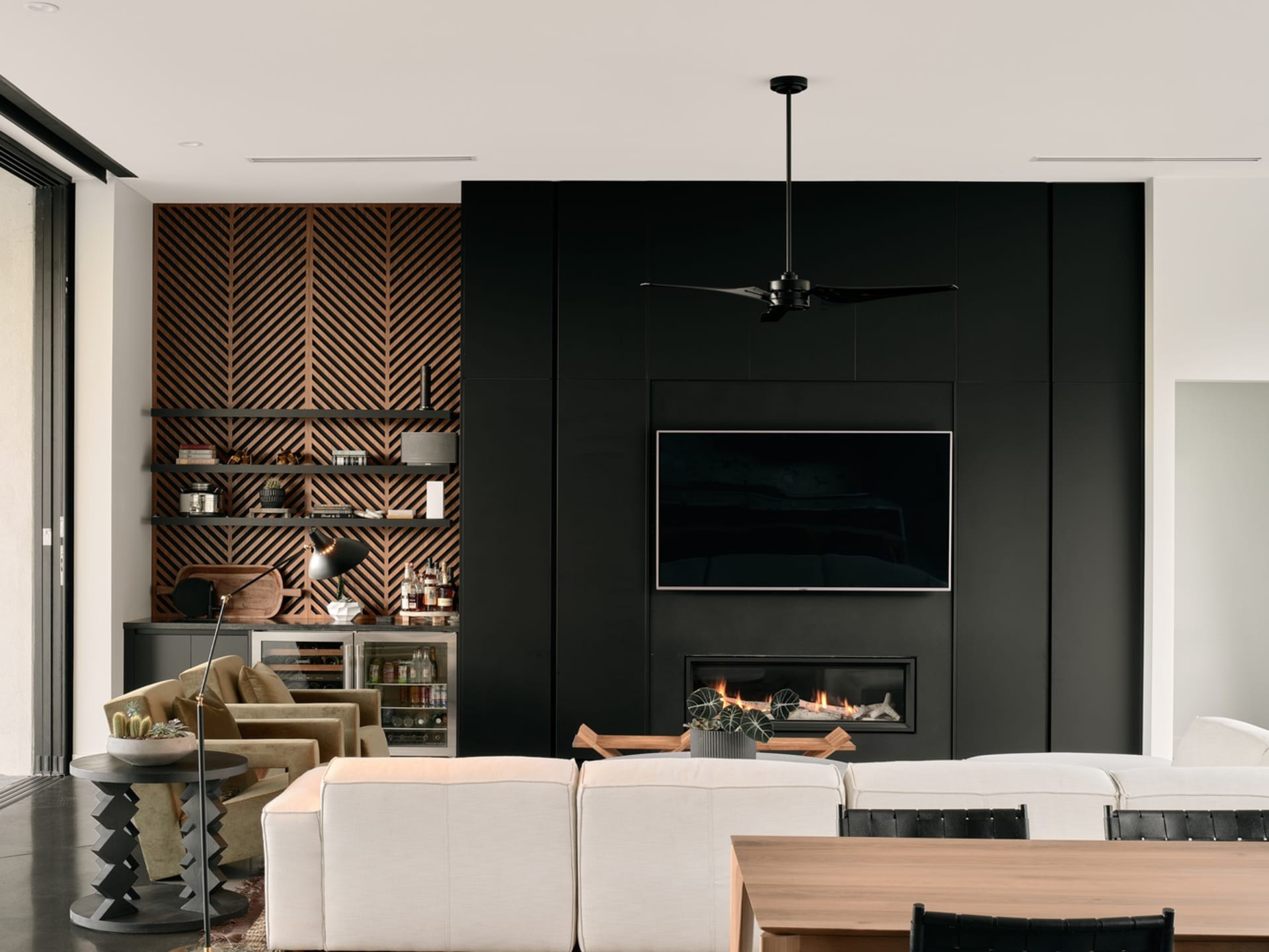 Modern living room with black walls and metal paneling, featuring a white sectional sofa, wooden coffee table, and black ceil