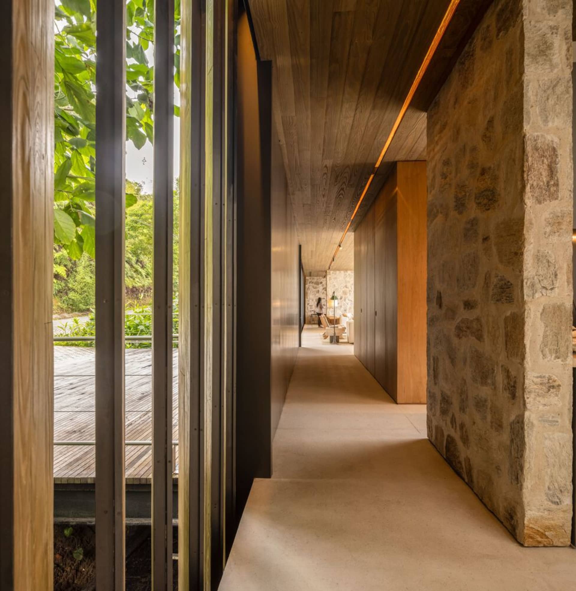 A modern corridor featuring exposed wooden beams, concrete floor, and glass walls.