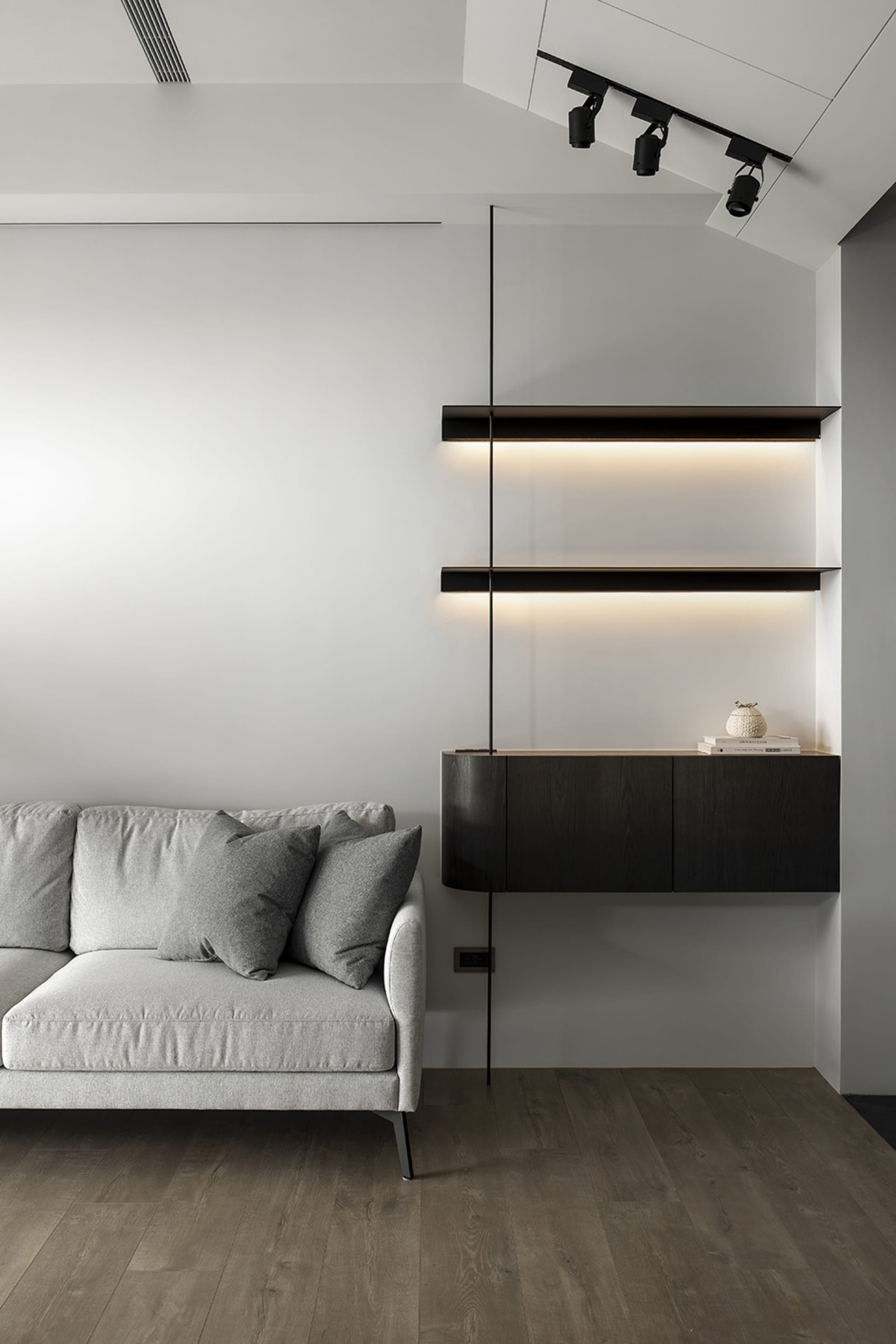 Modern living room with a white sofa, black shelves, and wooden flooring.
