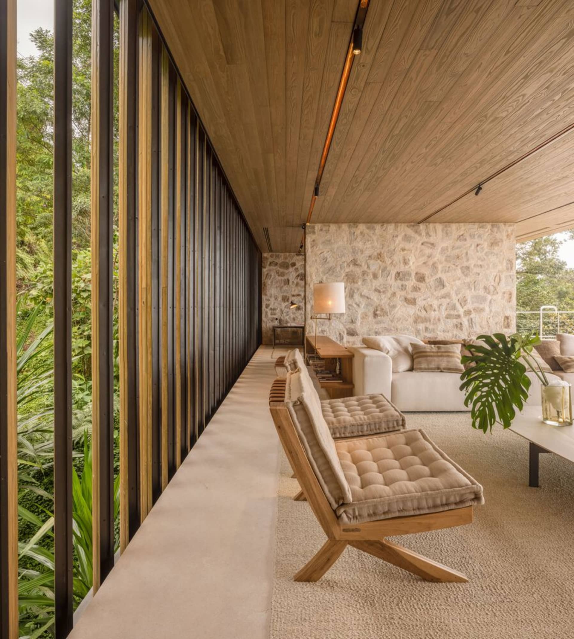 Modern living room with wooden furniture, concrete flooring, and stone accents.