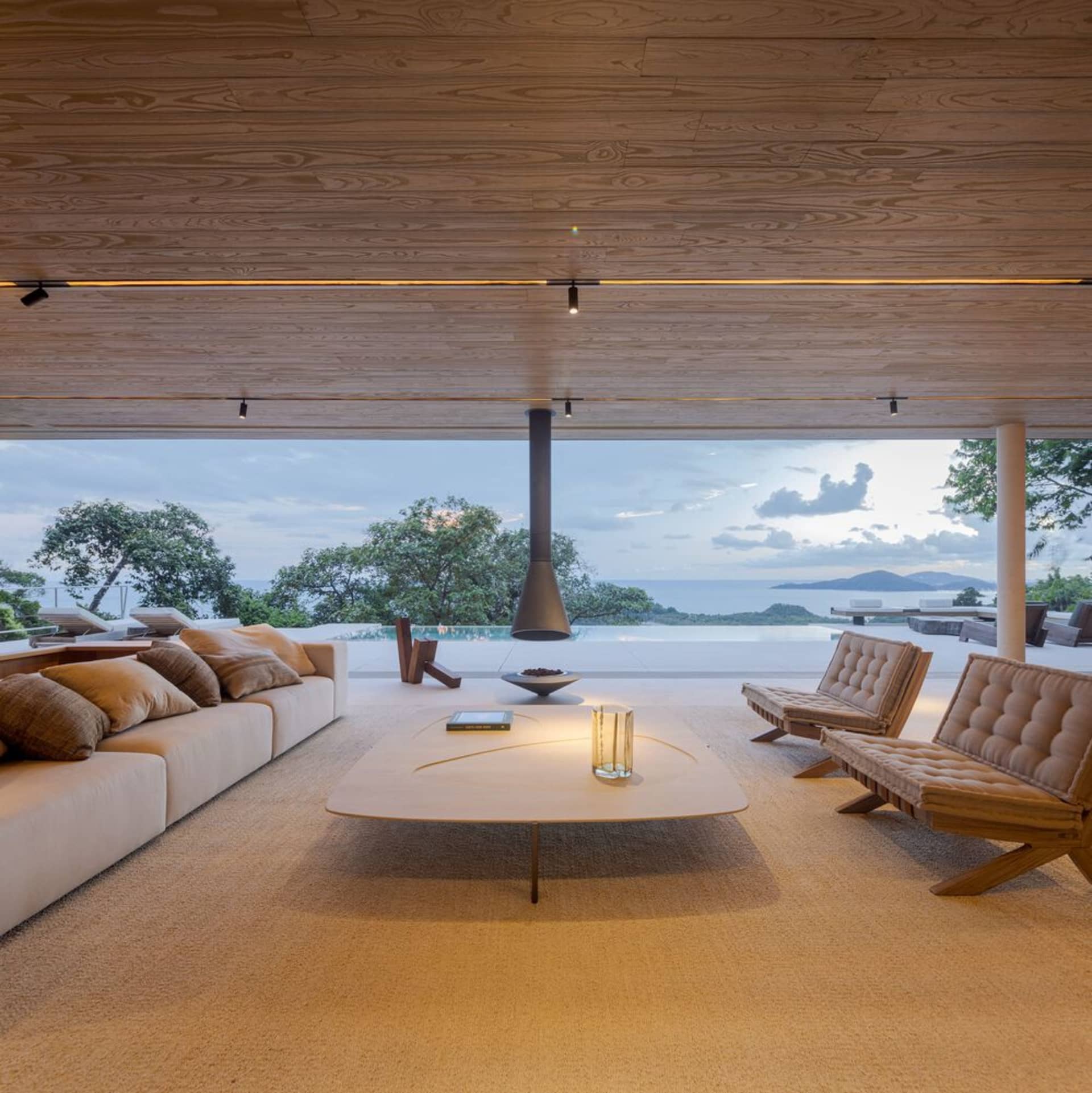 A modern living room featuring minimalist furniture, a wooden floor, and a view of the outdoors.
