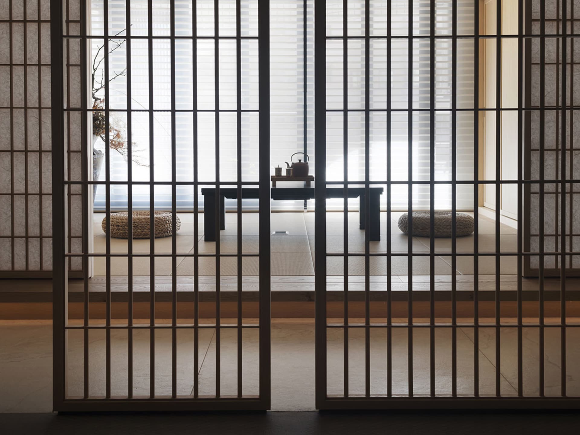 Modern living room with a dark wood floor, minimalist furniture, and large windows.