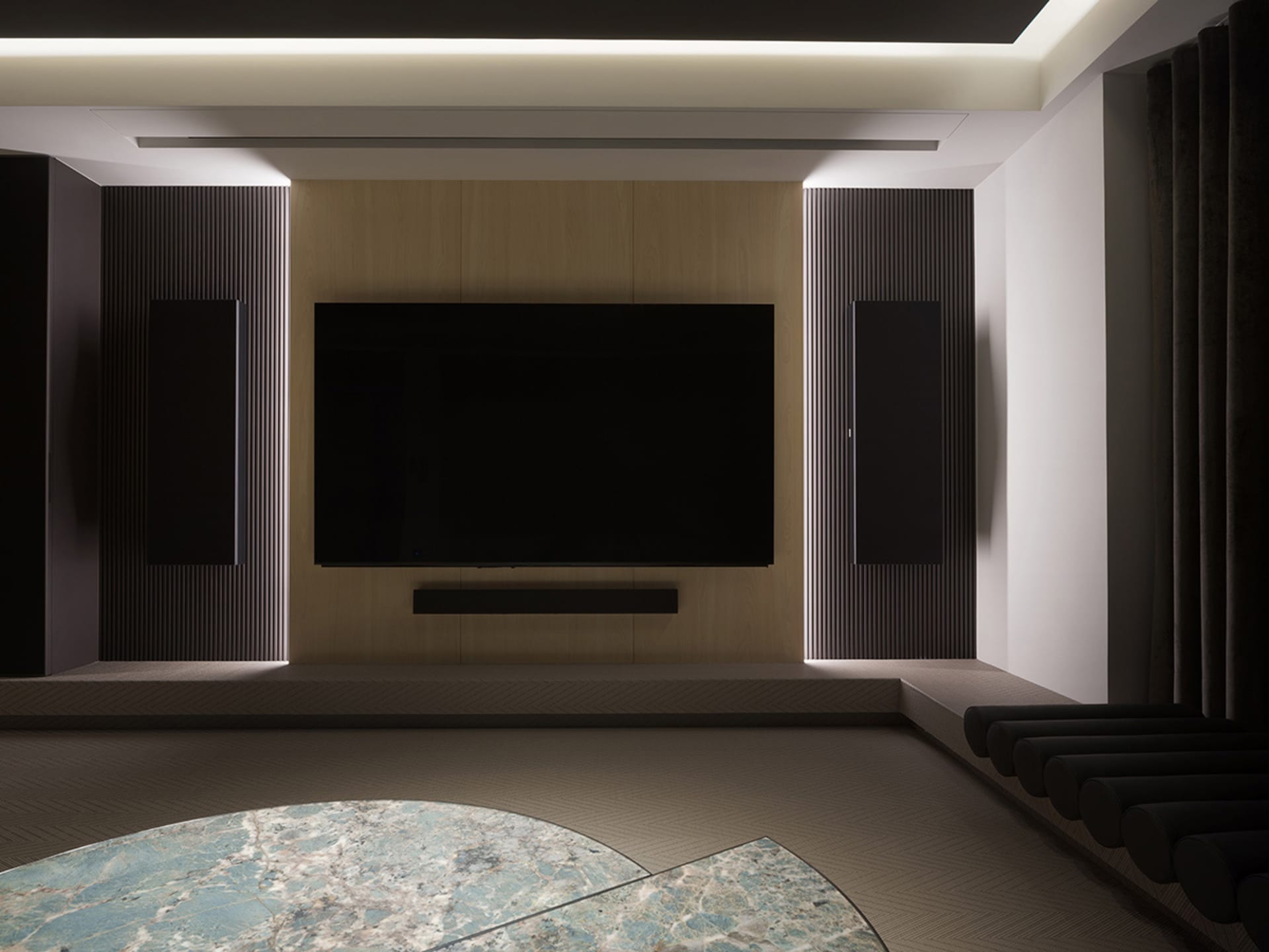 A modern media room featuring a large flat-screen TV, surround sound speakers, and wooden accents.