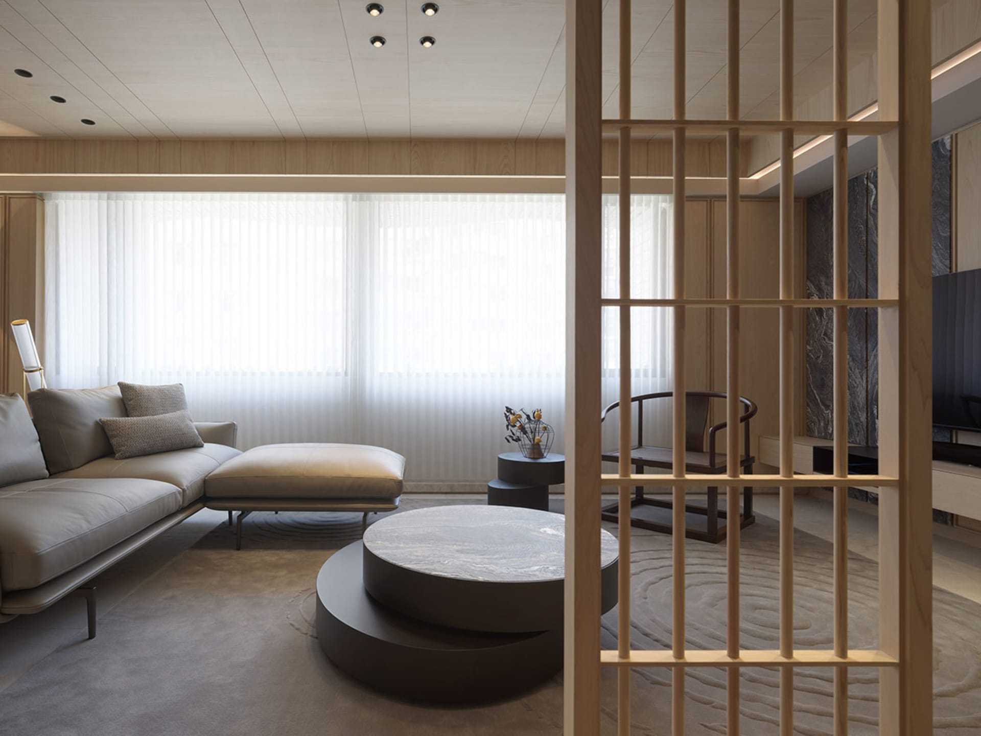 A modern minimalist living room with a wooden floor, white furniture, and a round marble coffee table.