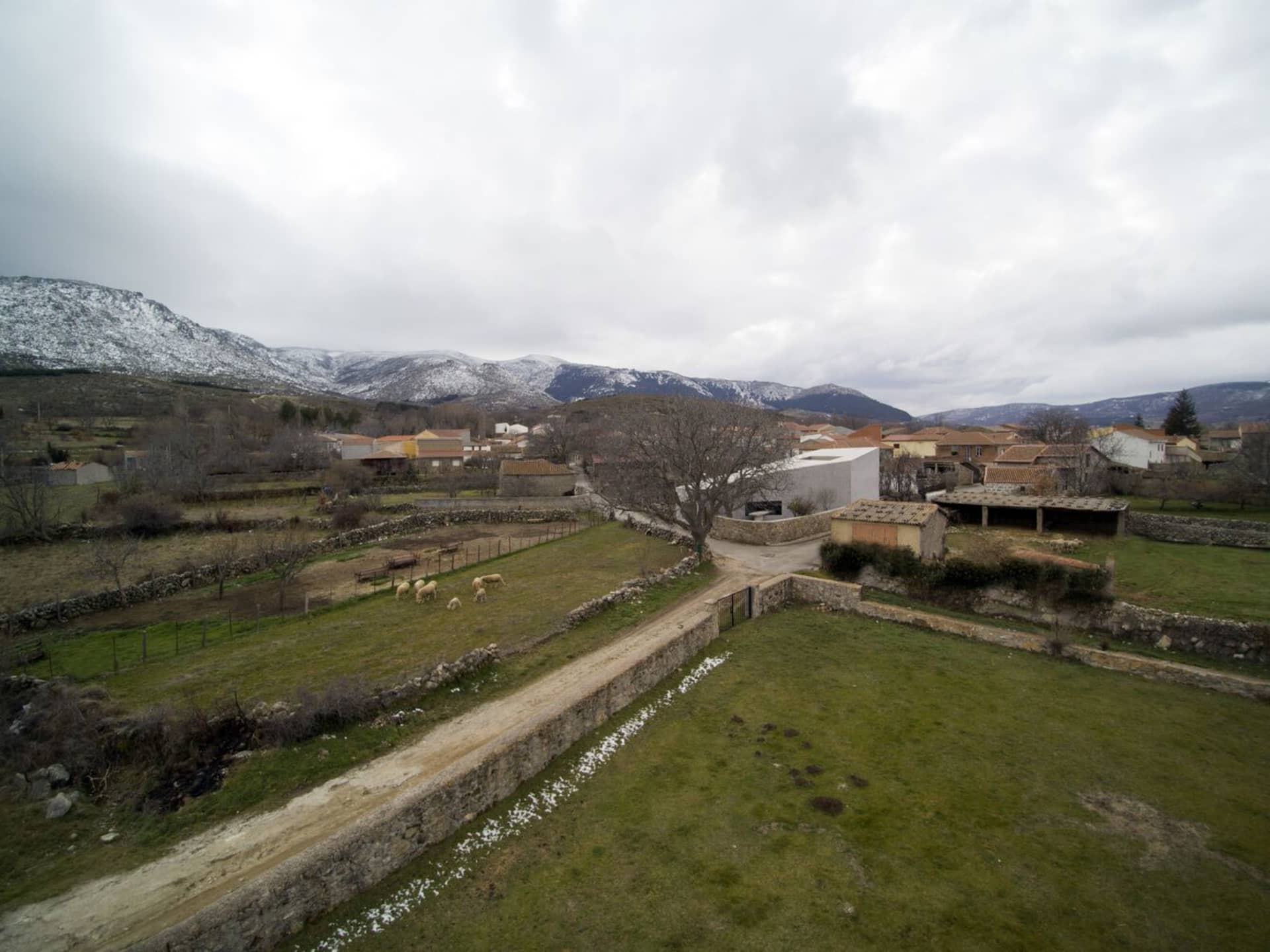 A view of a village in winter with snow-covered mountains in the background.