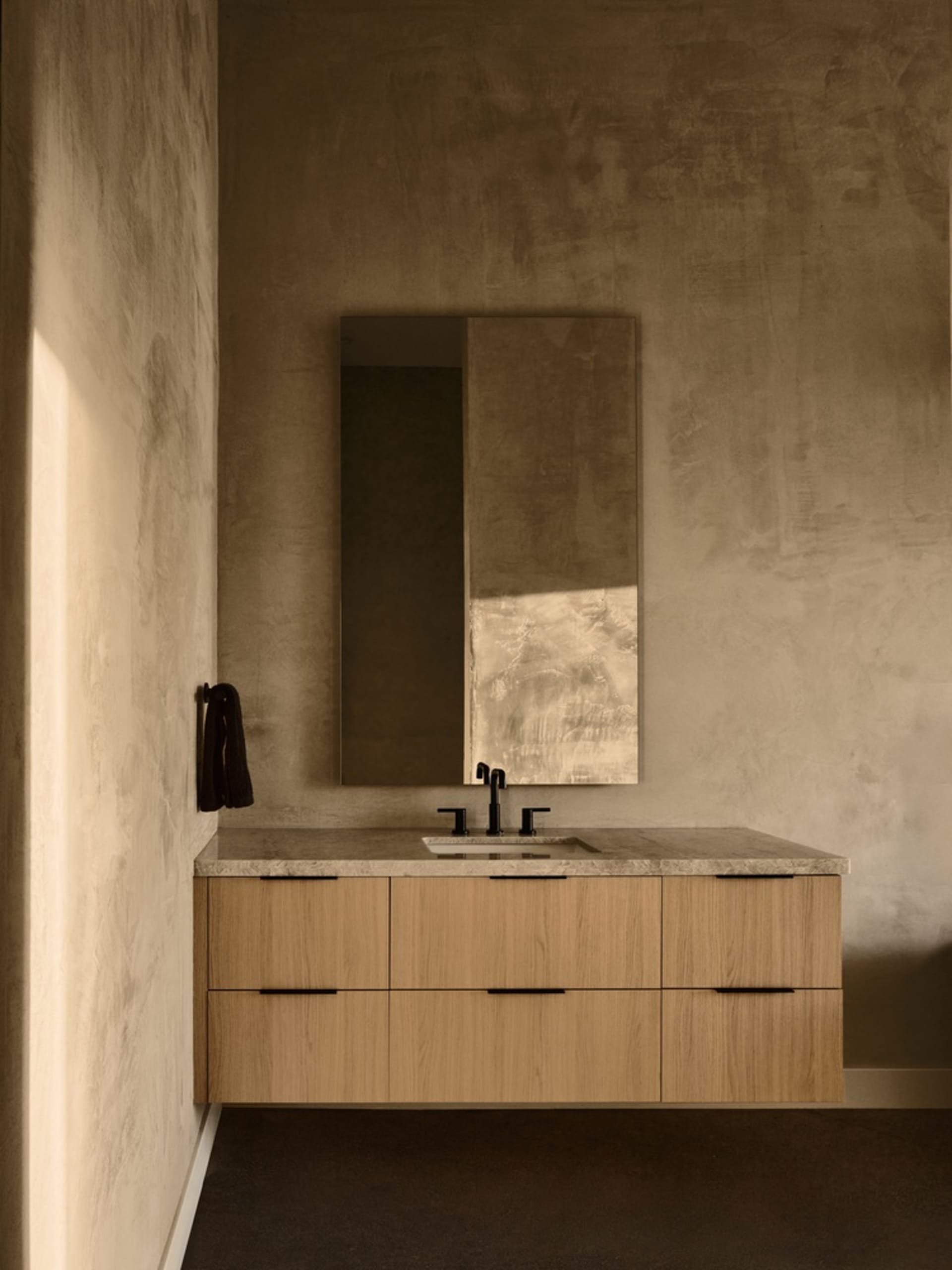Modern bathroom with a concrete vanity and faucet against a textured wall