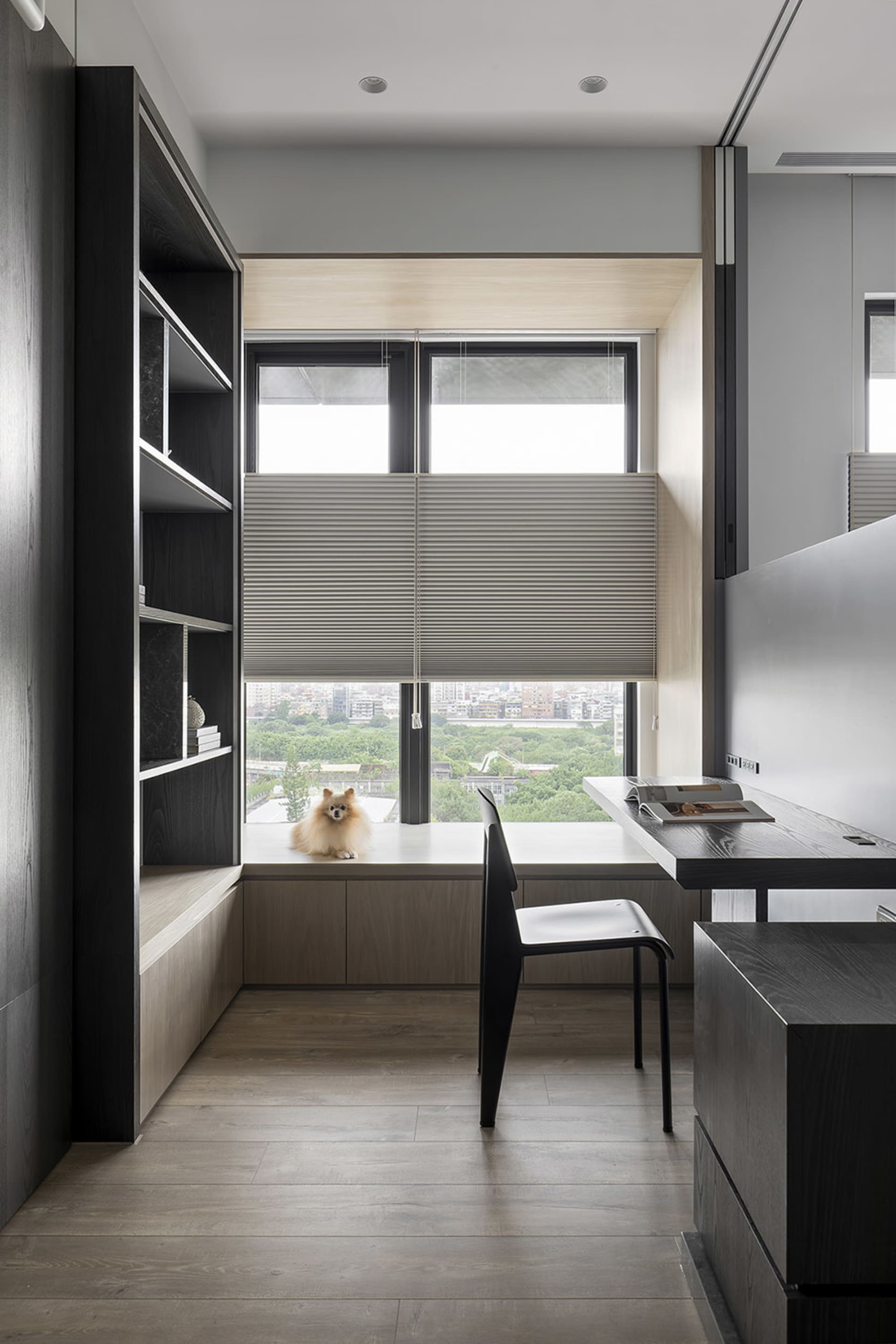 A modern home office featuring a wooden desk with a view of the cityscape outside the window.