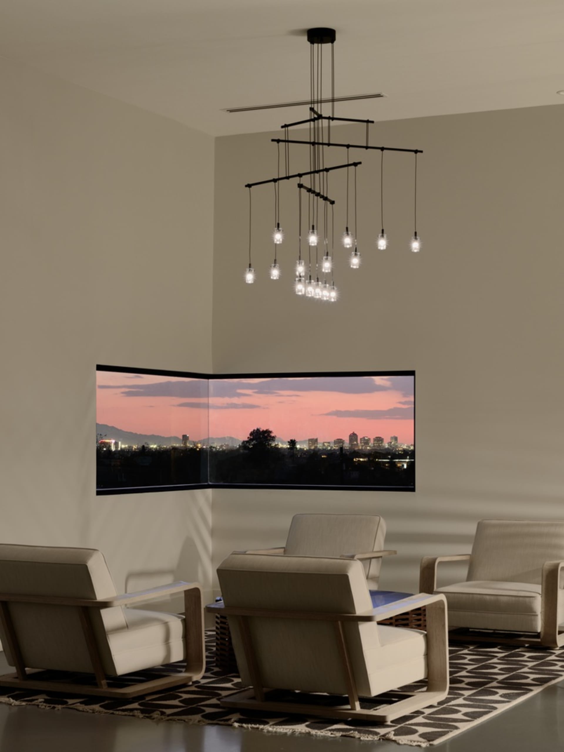 A modern living room with textured paint walls, minimalist furniture, and a large window overlooking a cityscape at sunset.