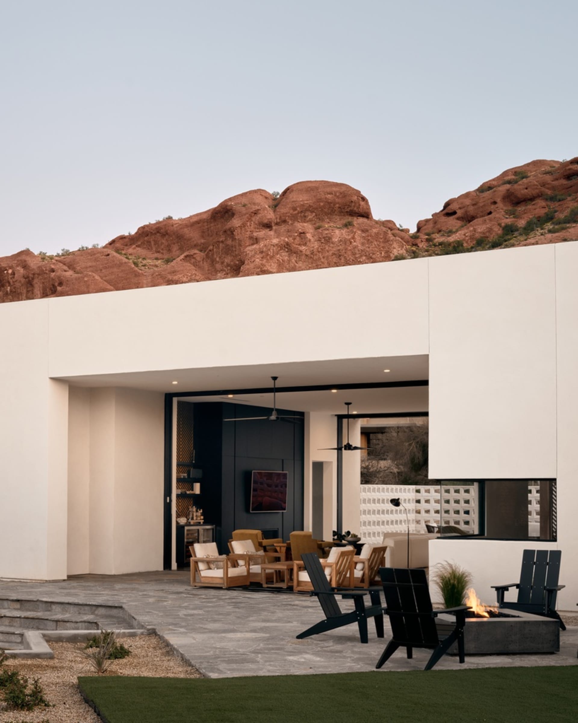 Concrete exterior of a modern residential building with red rock formations in the background.
