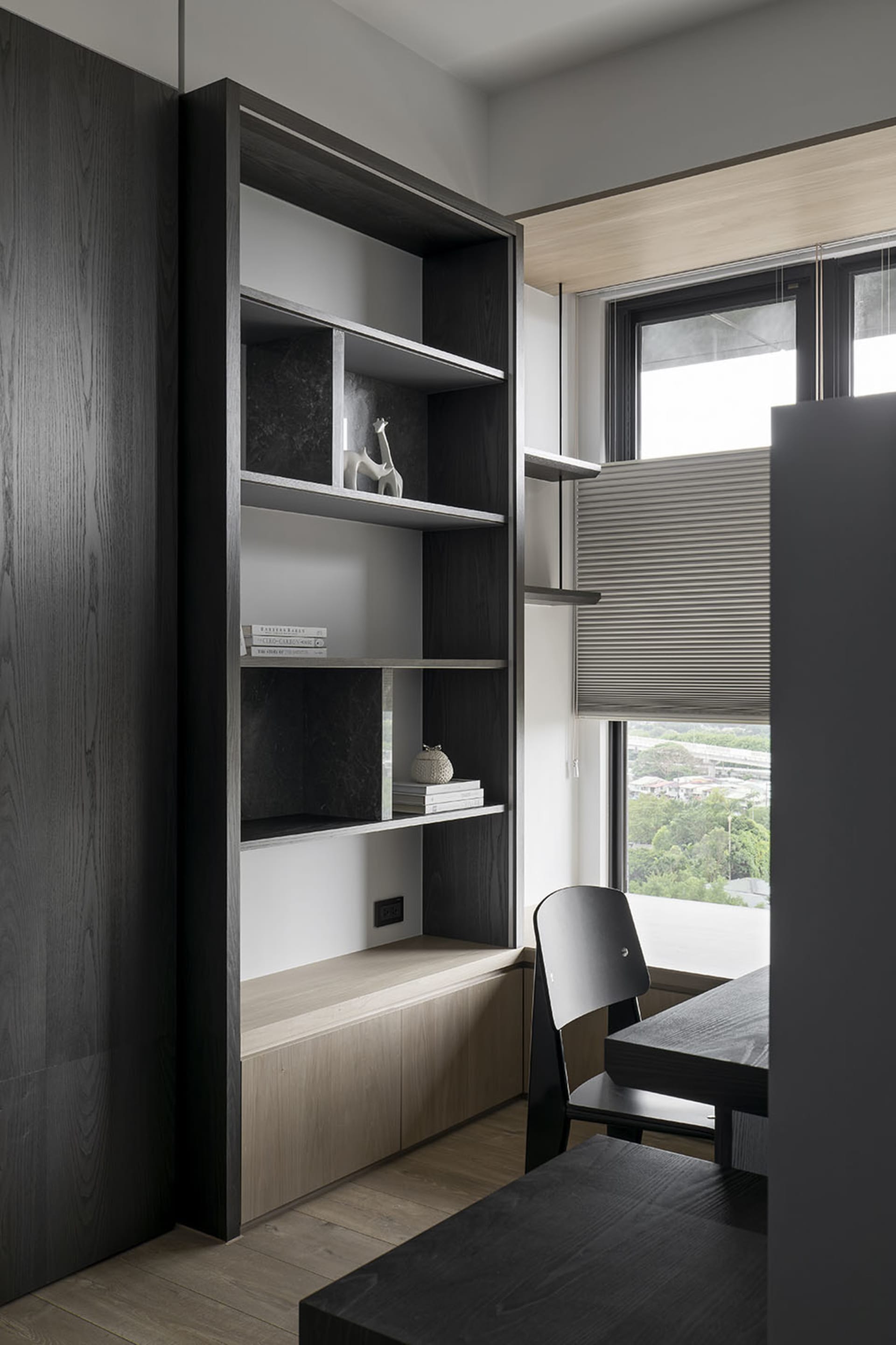 A modern minimalist workspace featuring dark wood furniture and shelves.