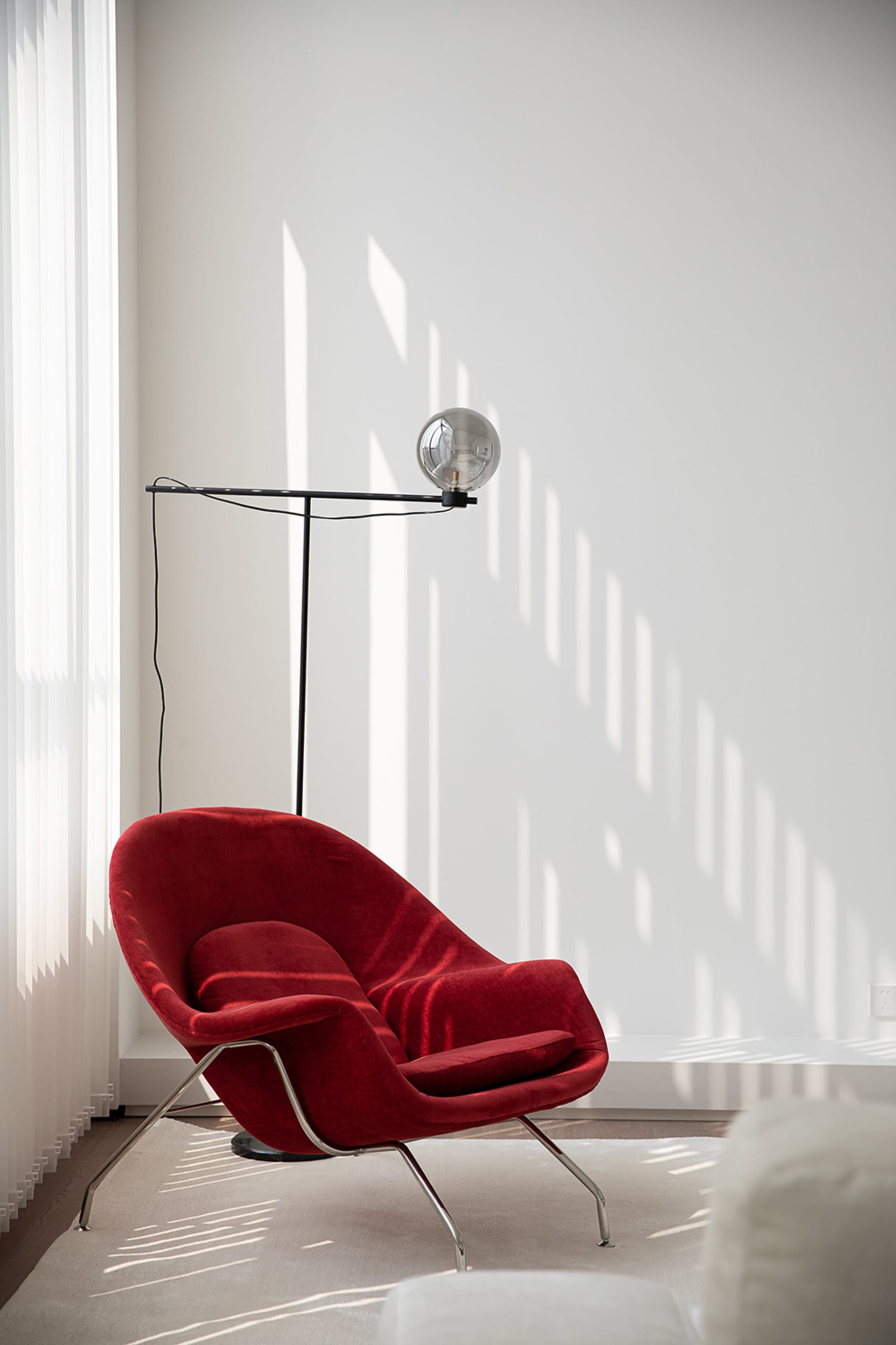 A modern red velvet chair in a contemporary living room setting, featuring a sleek, curved design.