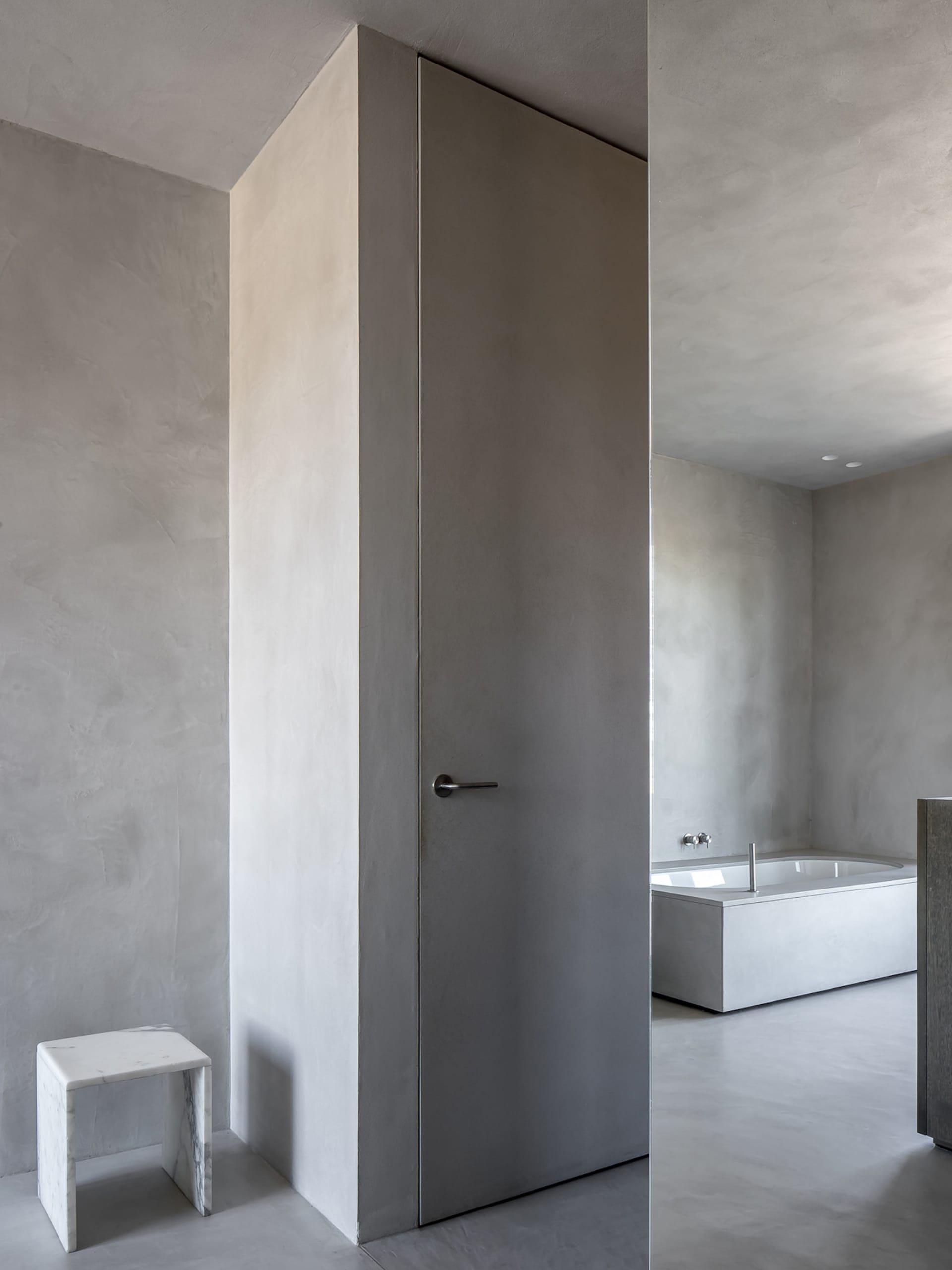 A sleek, modern bathroom with concrete walls and floor, minimalistic design, and a minimalist bathtub.