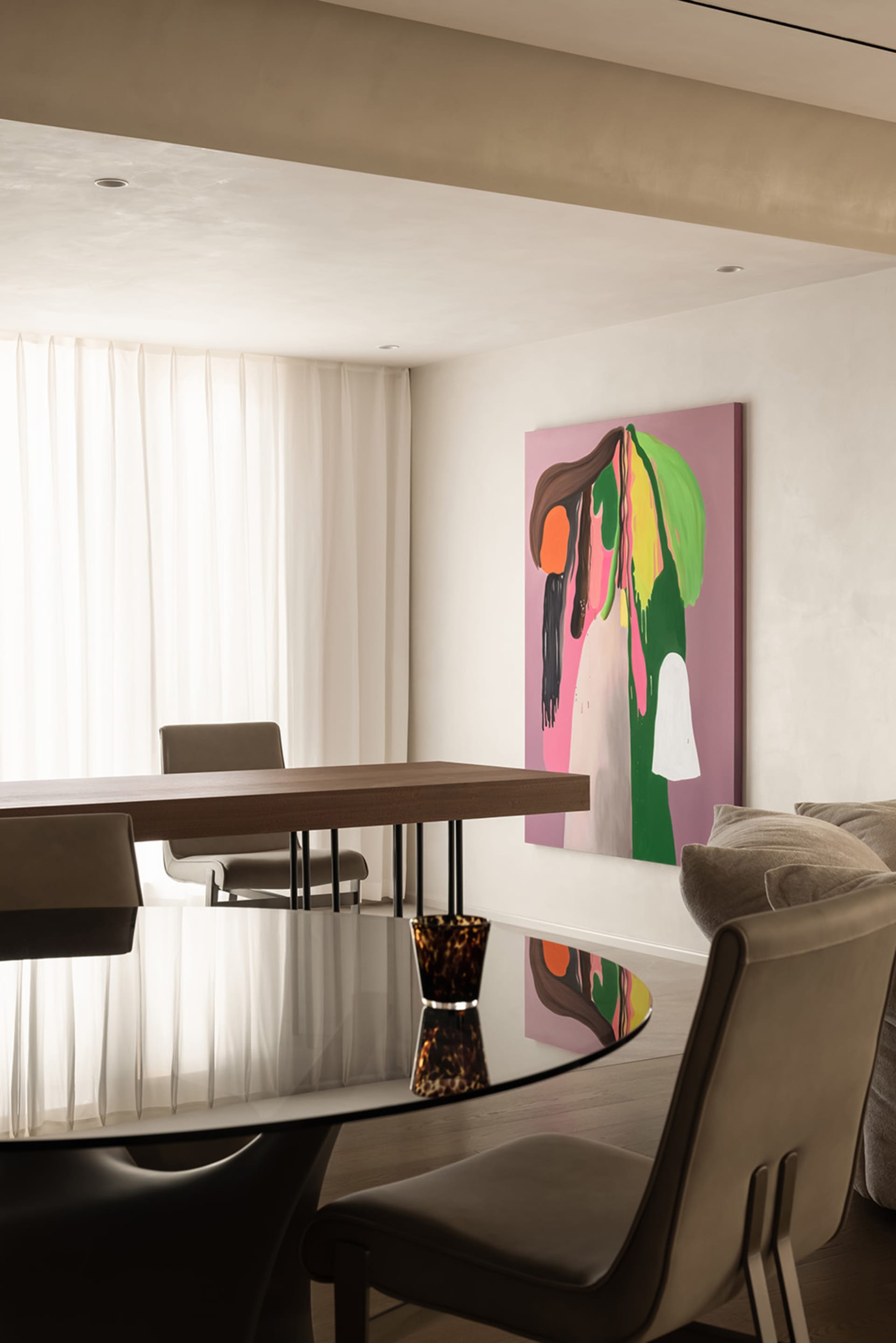 A modern dining room featuring a glass and wood table, leather chairs, and a colorful abstract painting on the wall.