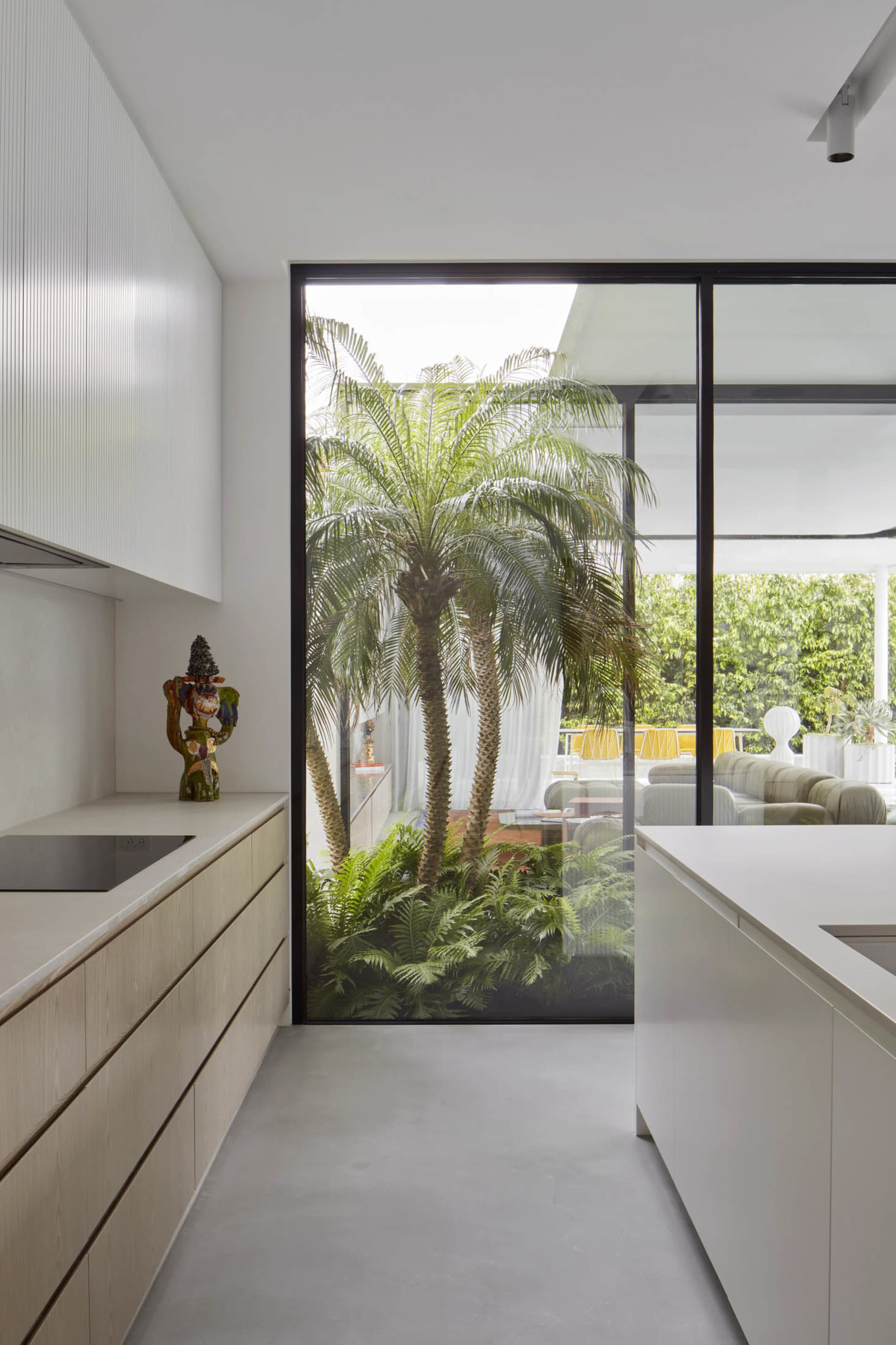 A modern kitchen featuring glass cabinets and concrete floors.