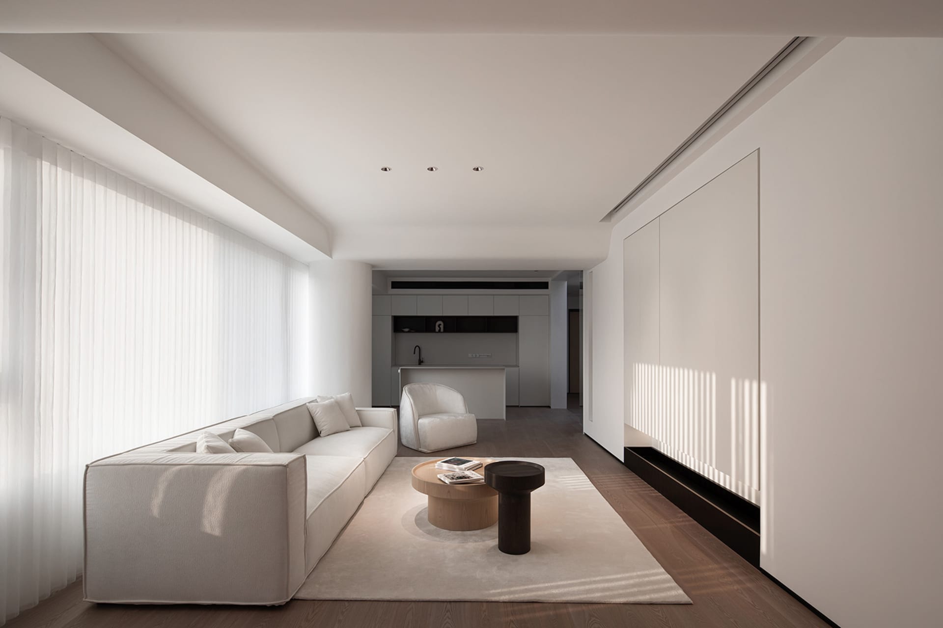 A minimalist living room with white furniture, featuring a comfortable sofa, a coffee table, and a sleek, modern design.