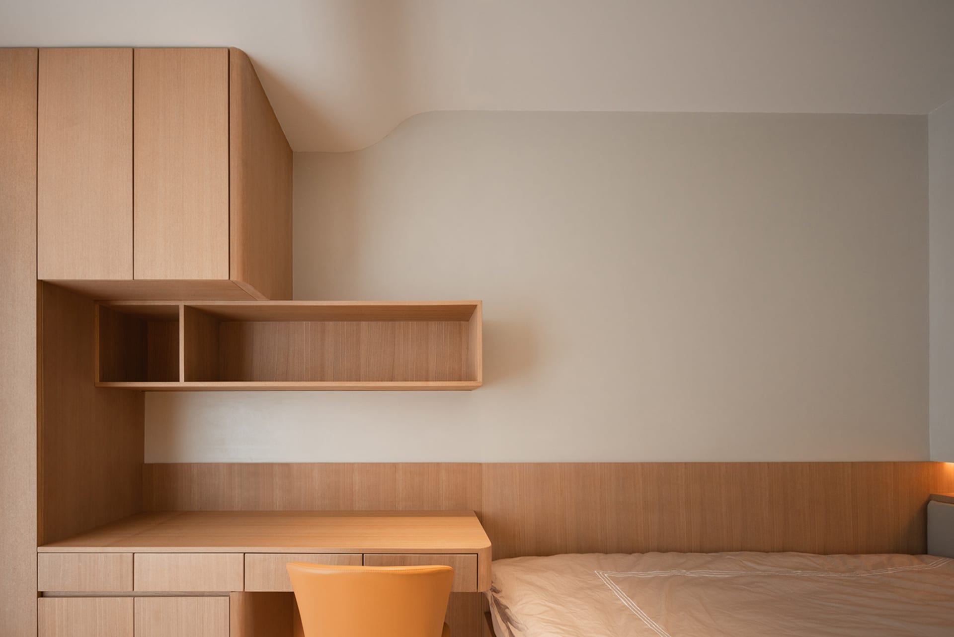A modern minimalist bedroom featuring wooden furniture and surfaces.