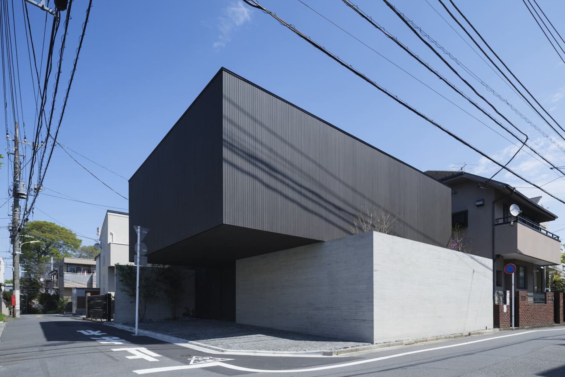 現代住宅採用黑色金屬外牆板與混凝土基座。