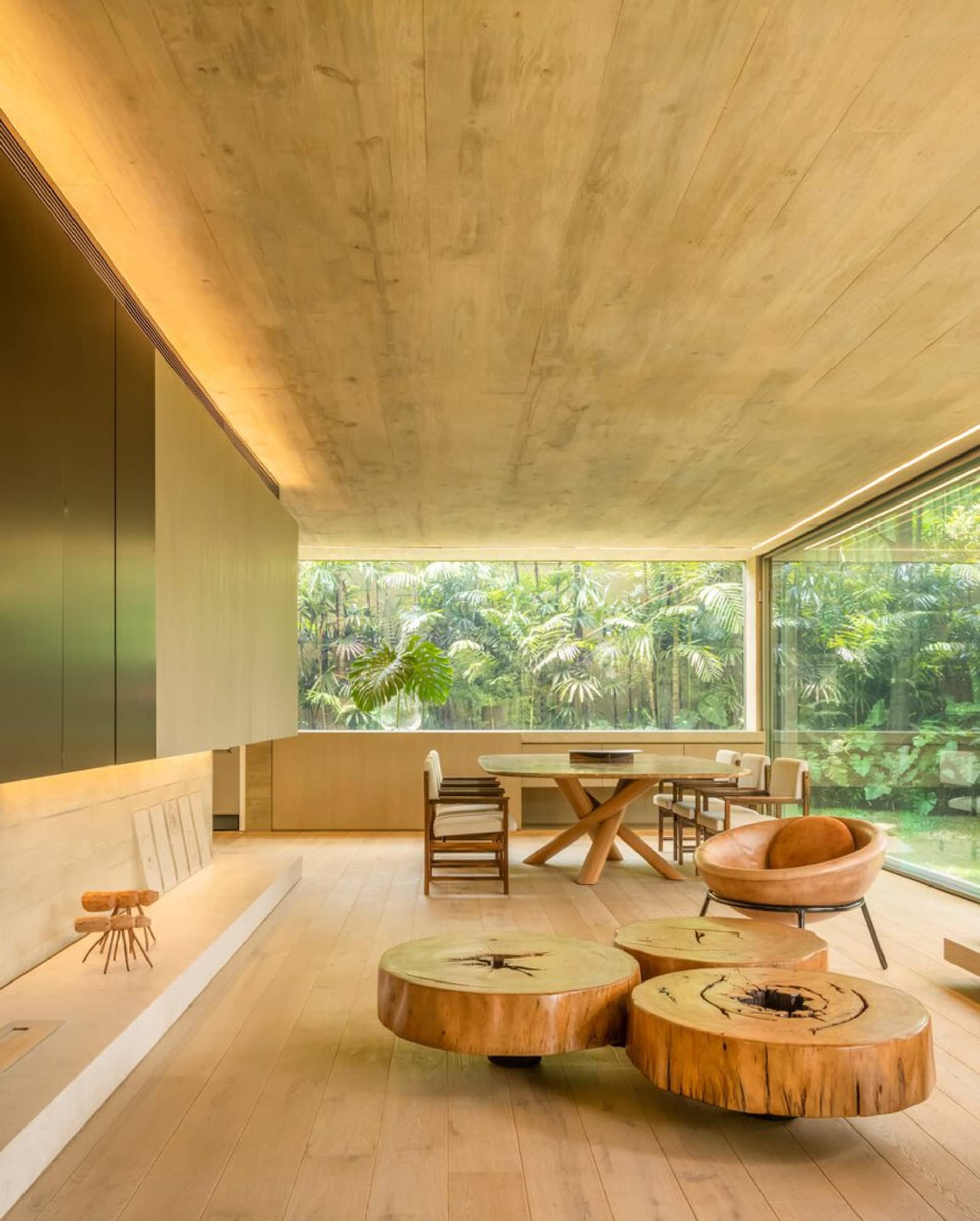 Modern living room featuring concrete coffee tables, wood flooring, and a large window overlooking a green landscape.