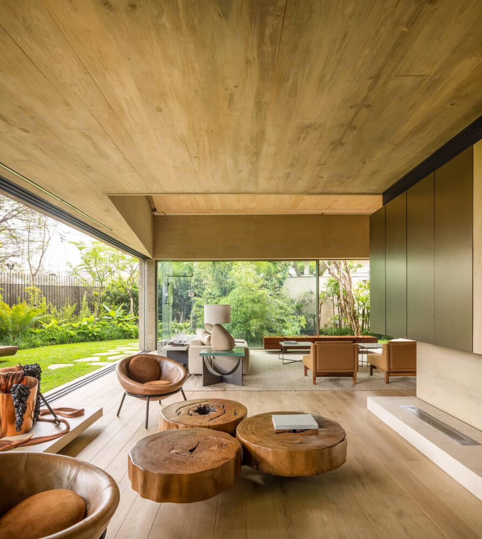 Modern living room with wooden tables, leather seats, and glass elements.