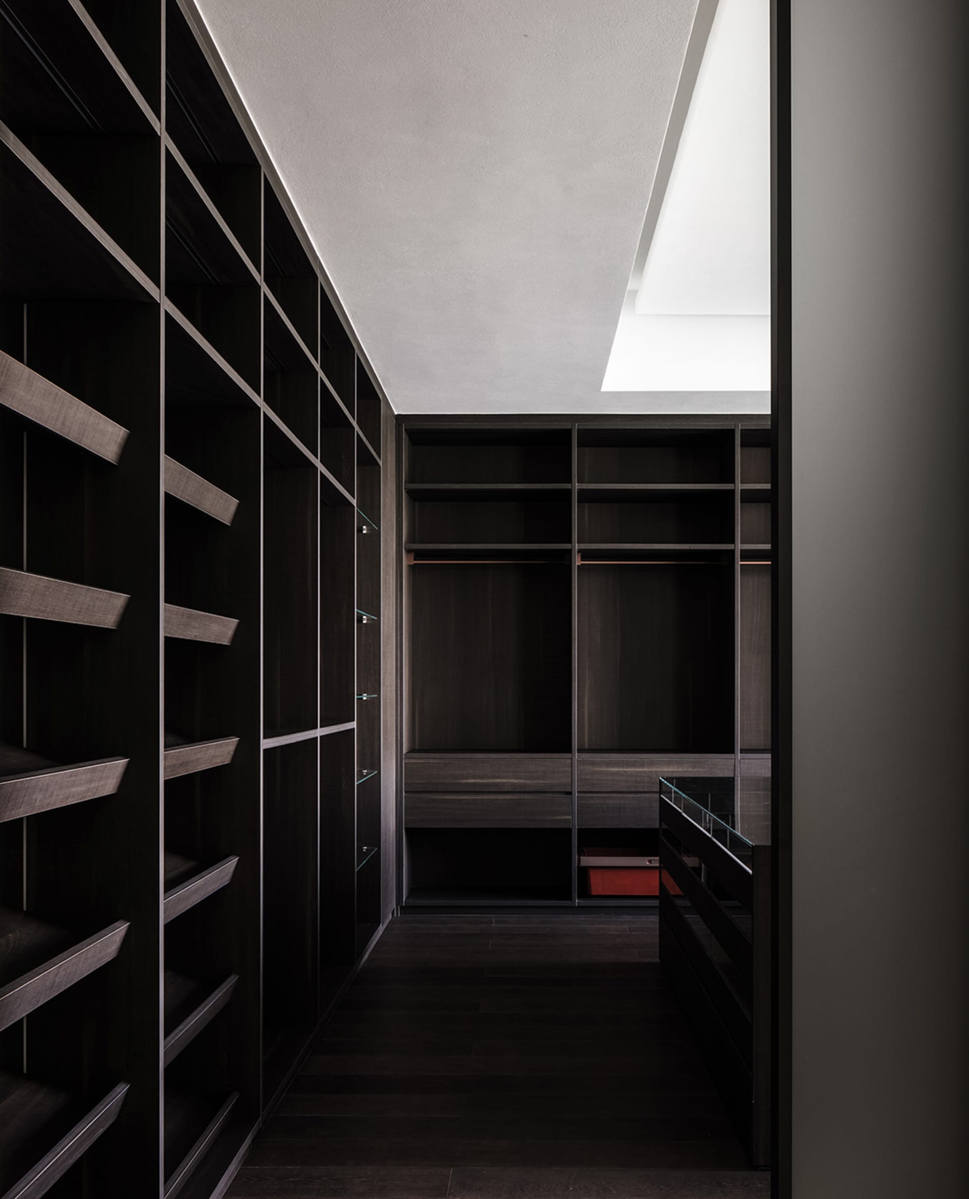 A minimalist dark wood closet with shelves, drawers, and skylights.