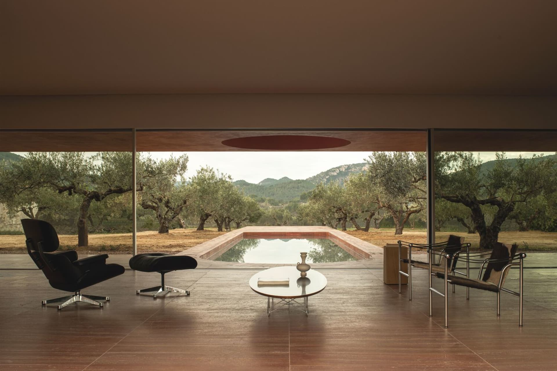 A modern interior design featuring wooden floors, glass walls, and a concrete swimming pool.