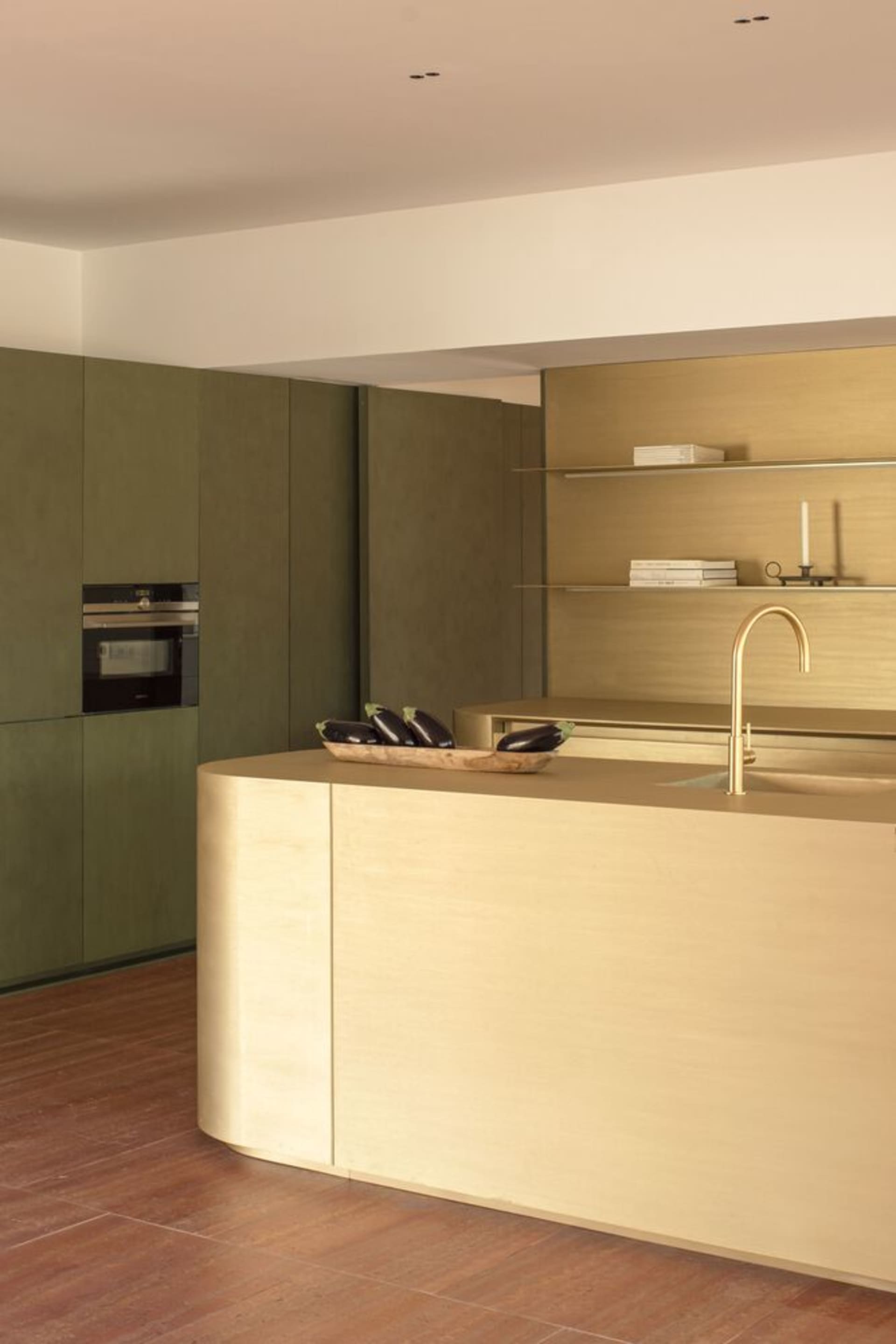 A modern minimalist kitchen with wooden countertops and shelves, featuring green cabinets and a light-colored island with a s