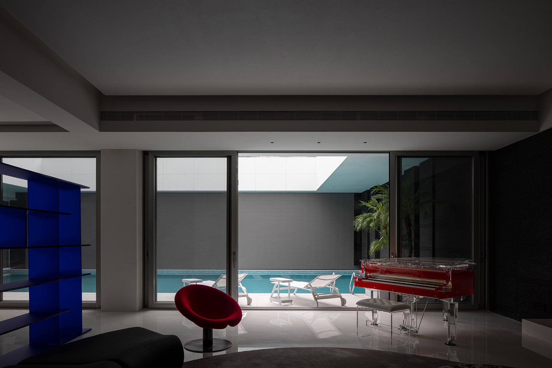 Modern living room featuring a concrete wall, floor-to-ceiling glass windows, and a minimalist interior design.