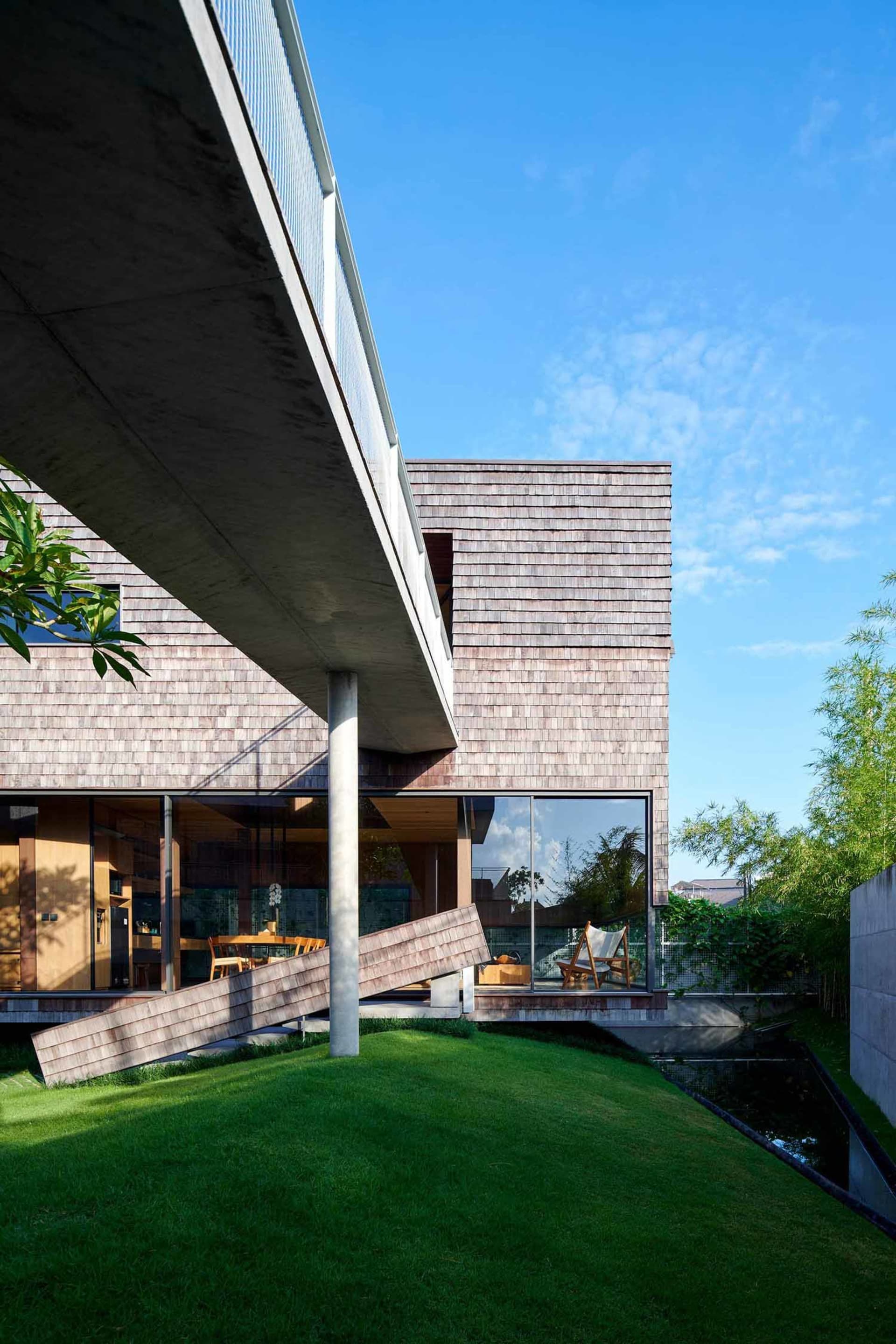 Modern residential architecture featuring wooden shingles, concrete, and glass elements.