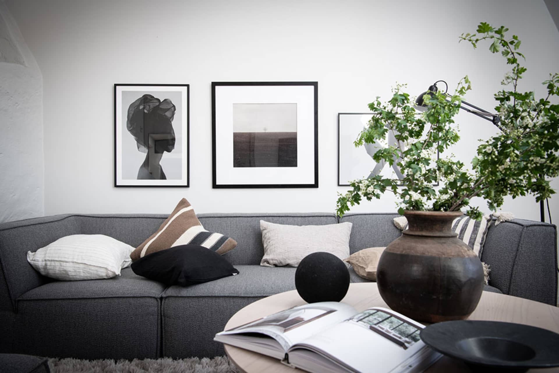 A modern, minimalist living room featuring a comfortable sofa adorned with neutral throw pillows and accentuating a floral ar