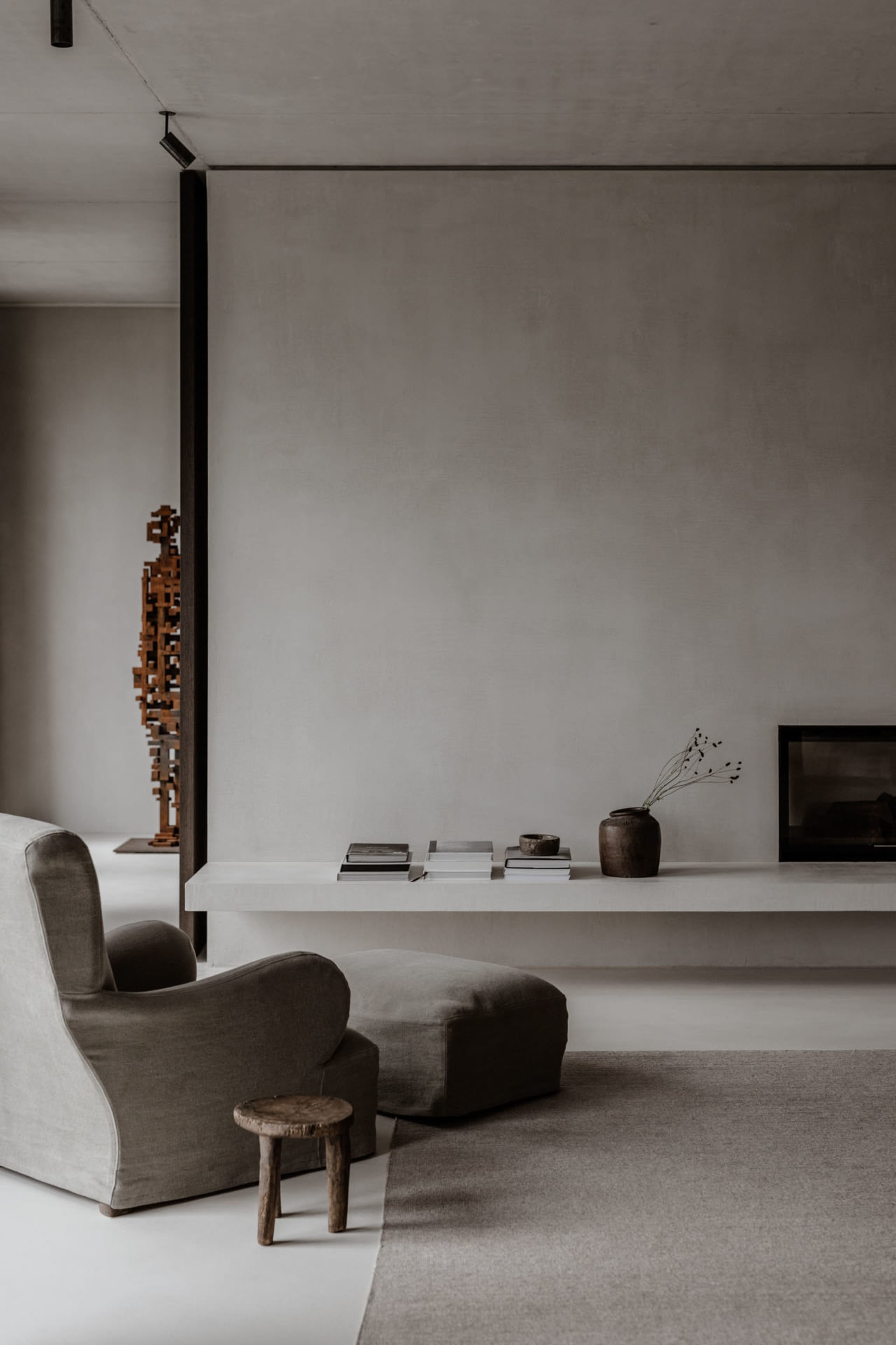 A minimalist living room featuring concrete surfaces and wooden elements.