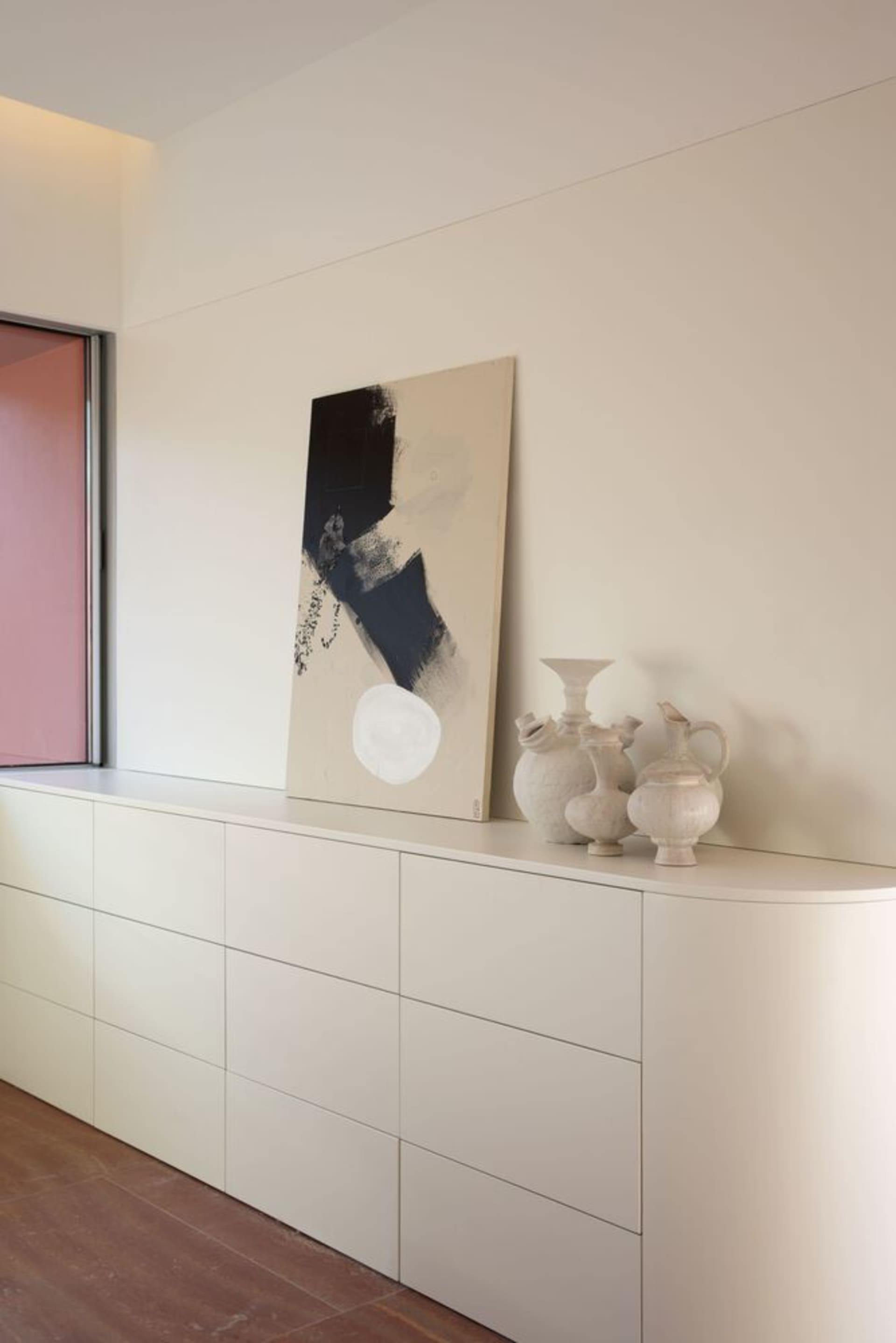 A minimalist interior featuring ceramic vessels on a white cabinet.