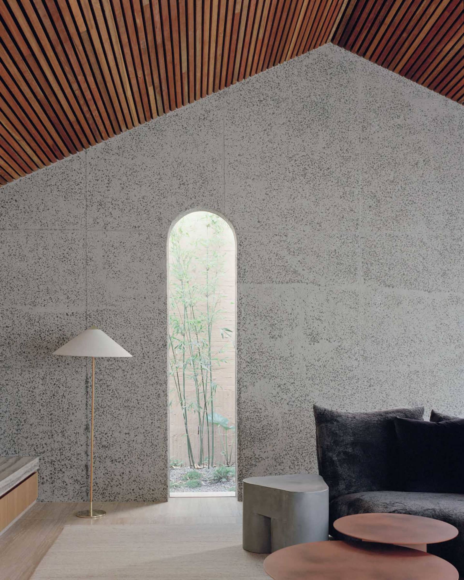 A modern living room with concrete walls and wooden ceiling.
