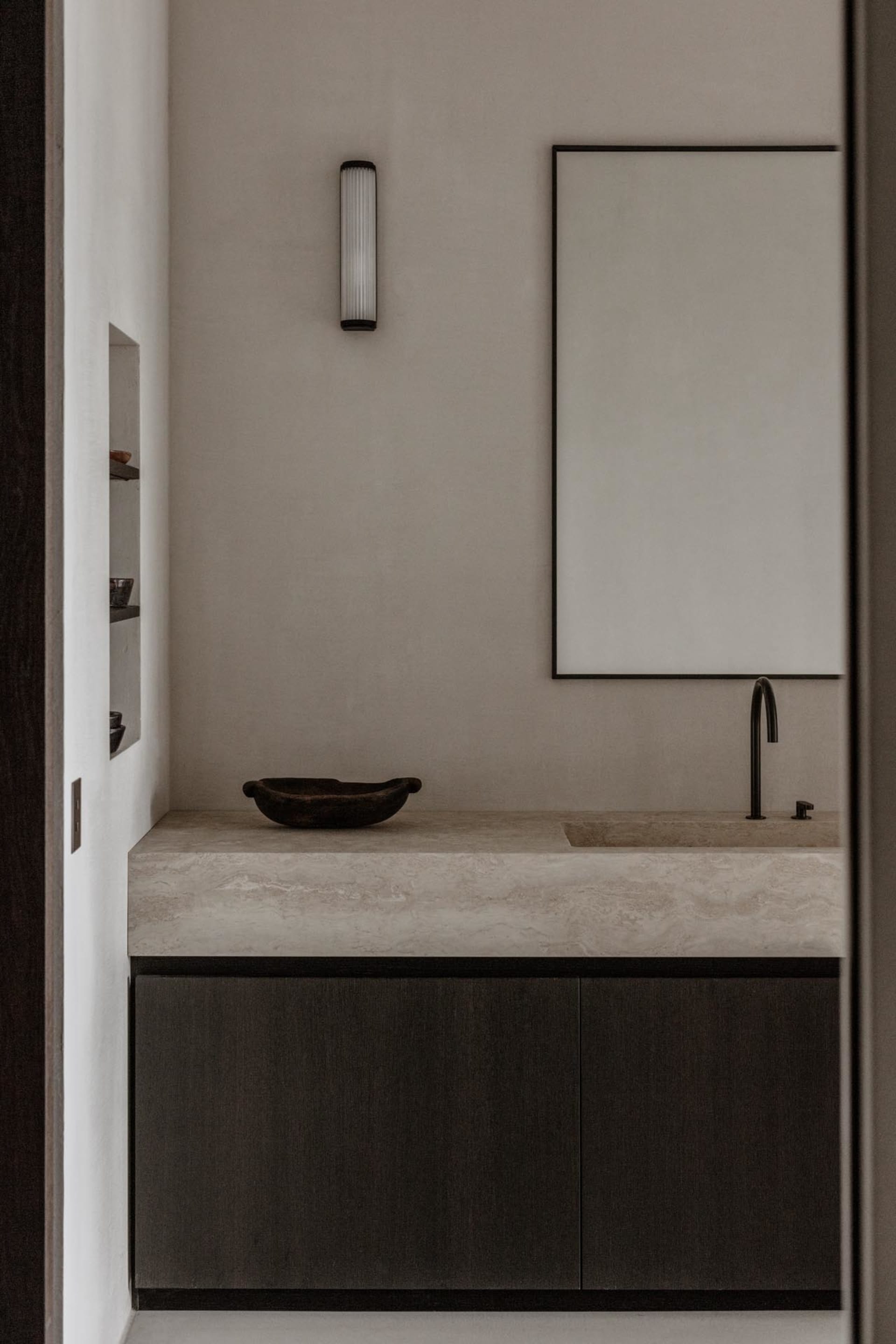 Modern bathroom featuring a concrete countertop with a sink, minimalist cabinet, and a rectangular mirror.