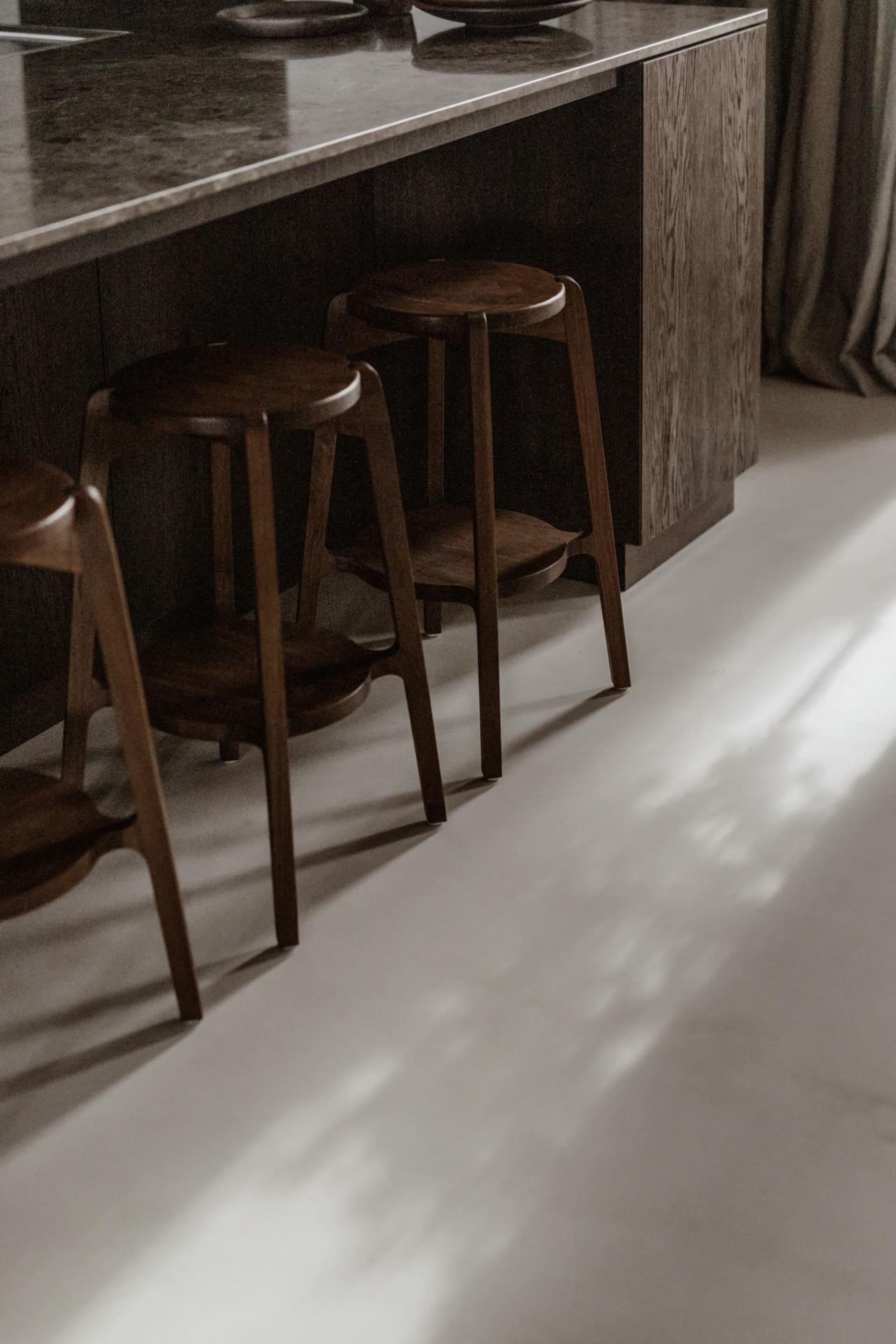 A modern kitchen with dark wooden stools and a polished countertop.