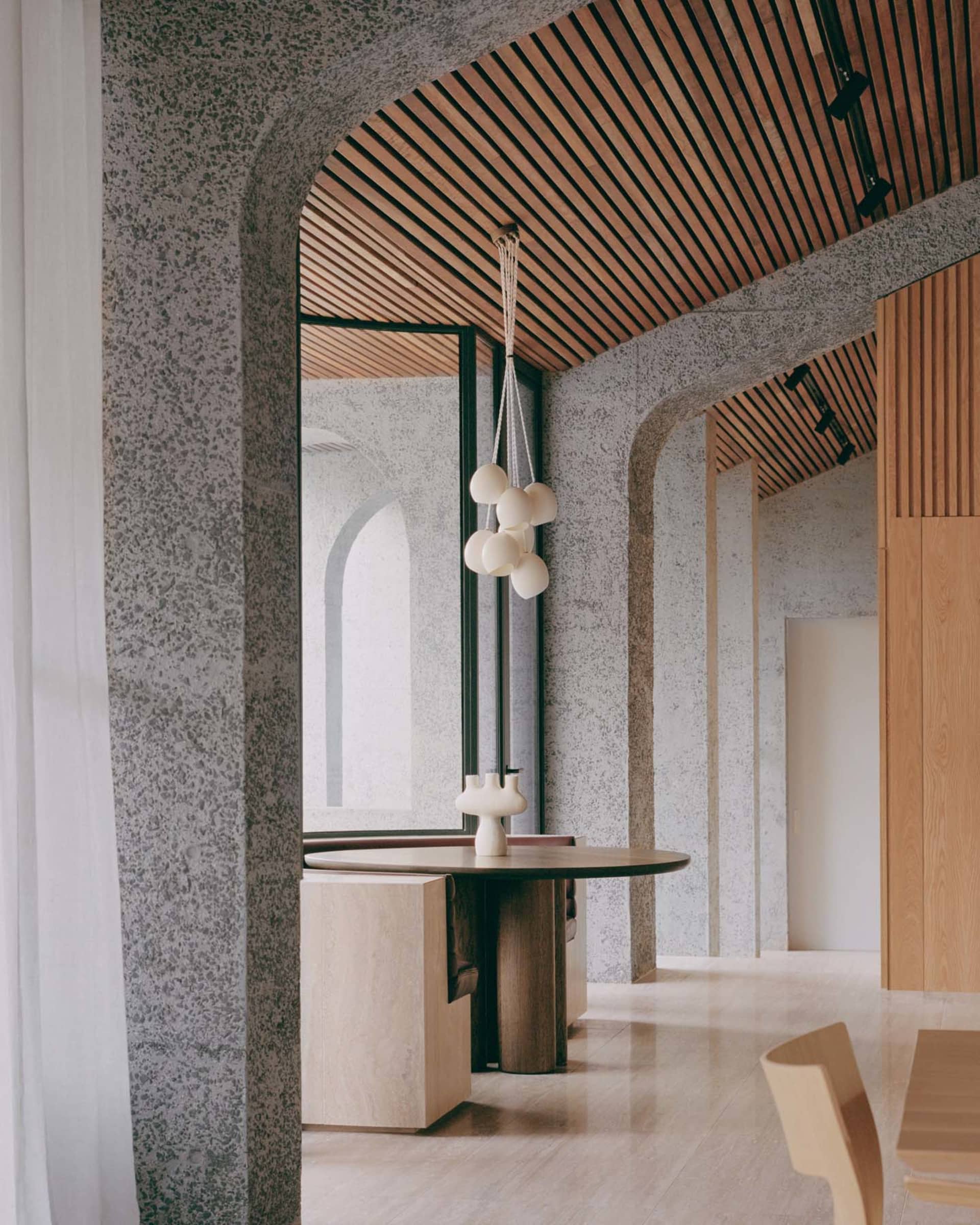Modern industrial-style lobby with concrete walls and slatted wooden ceiling.