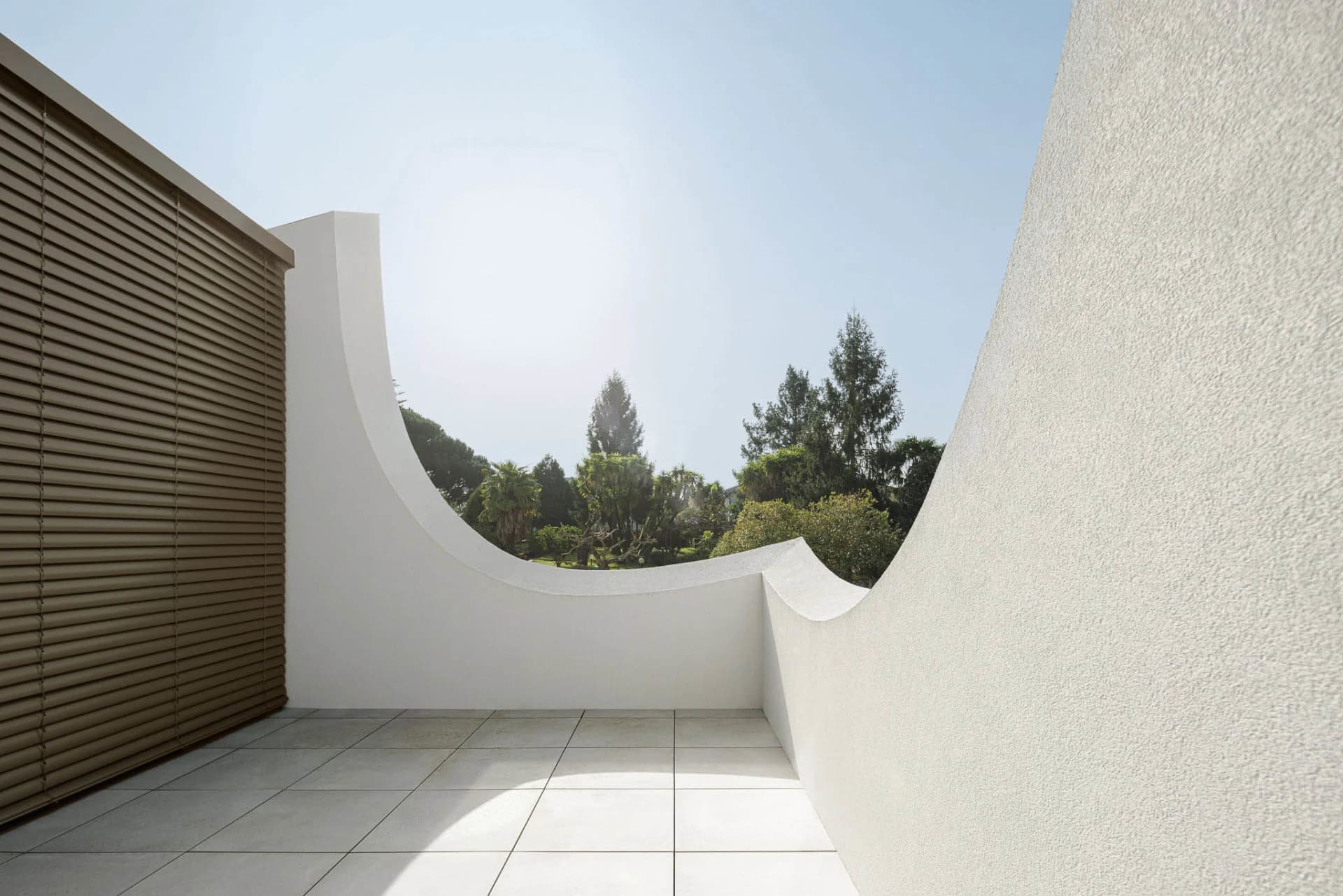 An architecturally minimalist balcony featuring concrete walls and a curved design.