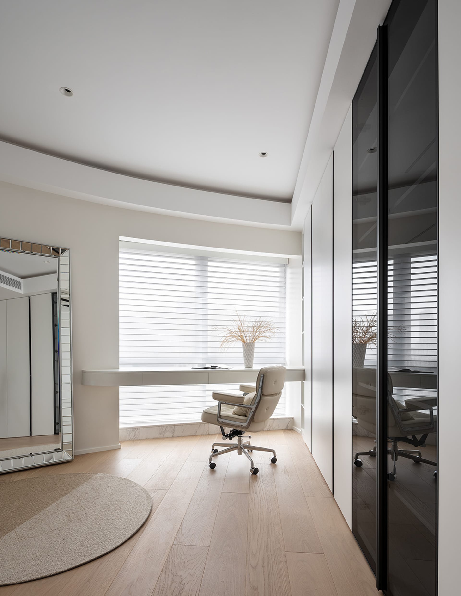 A modern minimalist home office featuring a white marble desk and chair, with sleek white furniture and natural light streami